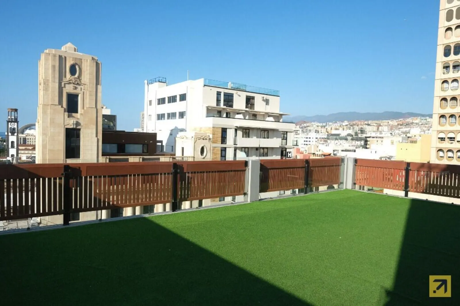 Hotel Adonis Plaza: A rooftop with artificial grass, a wooden fence
