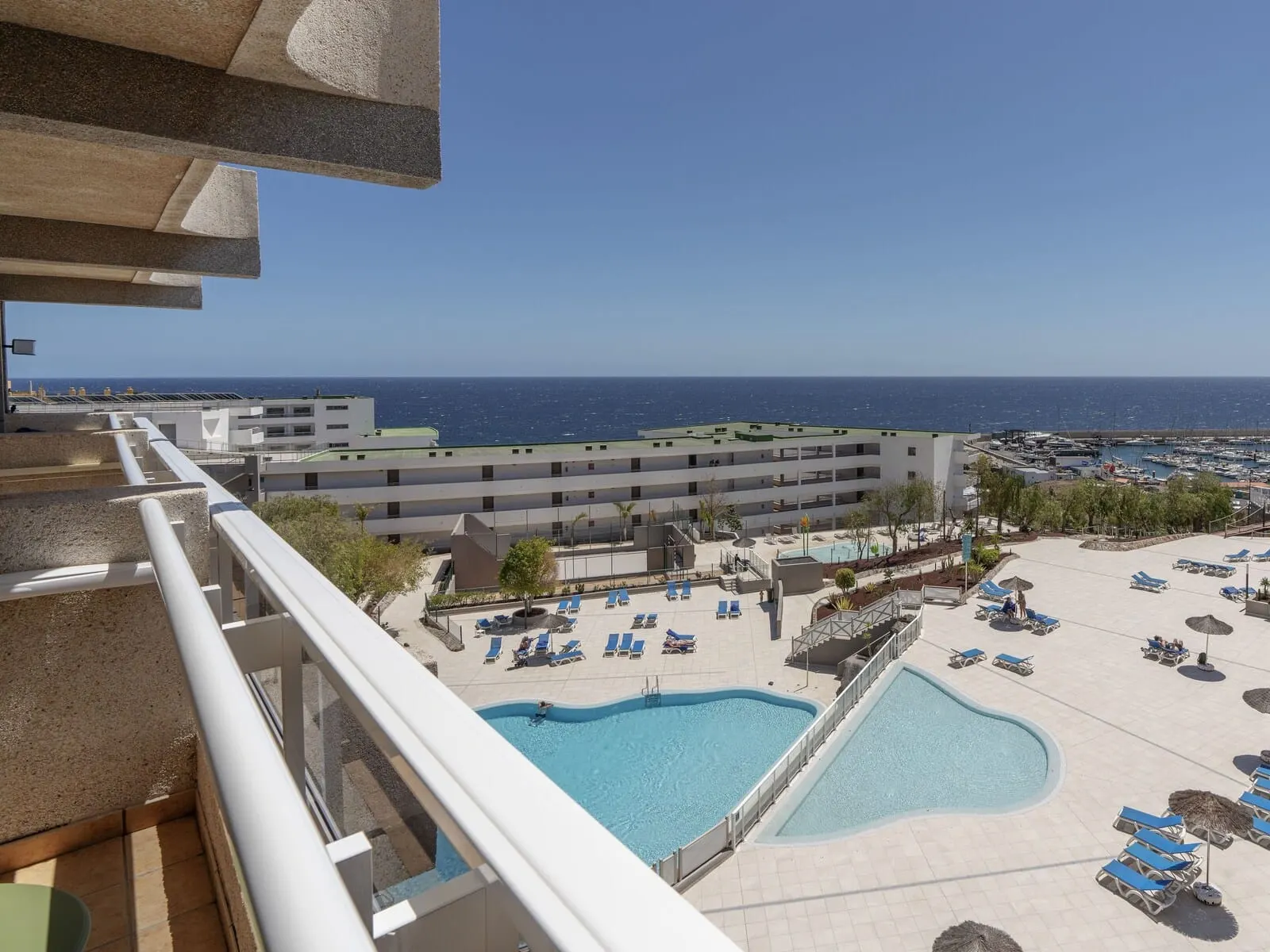 Alua Atlántico Golf Resort: A hotel with a pool area, multiple lounge chairs, and a view of the sea