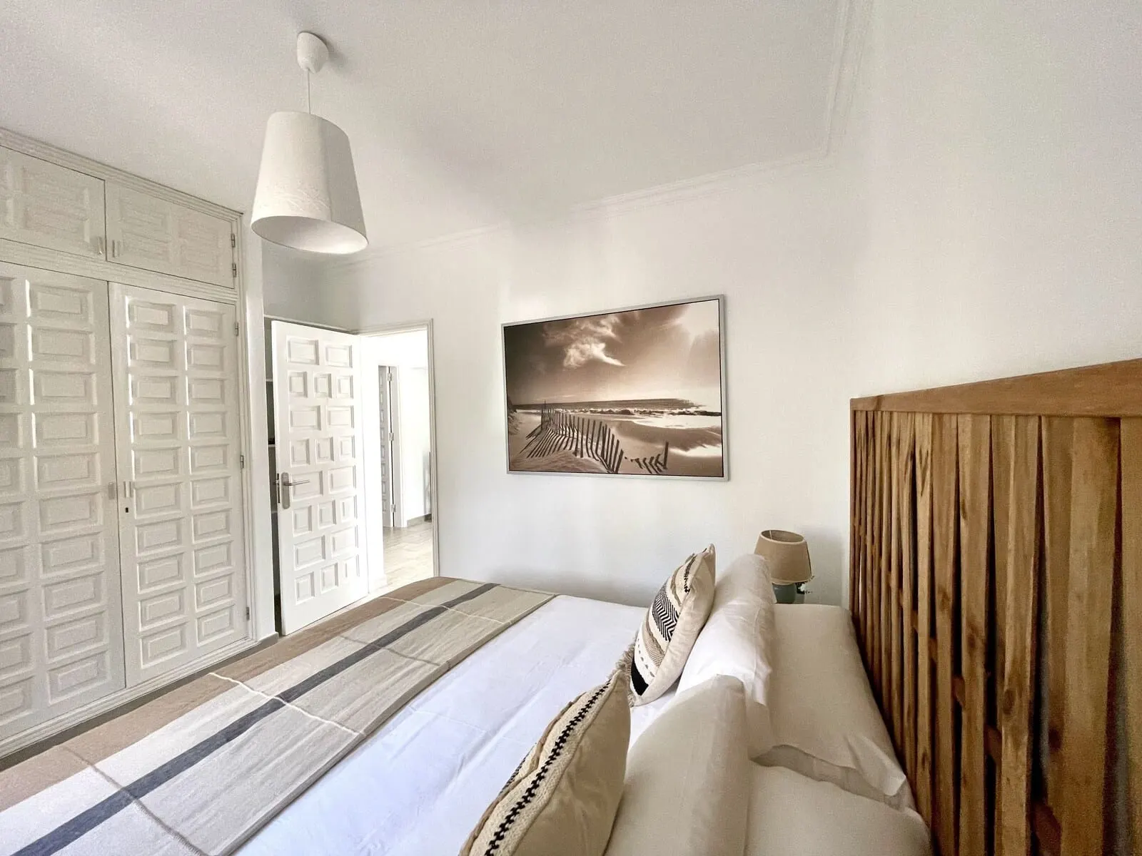 Hotel El Patio: A bedroom with a bed, a wooden headboard, a white door, a framed picture on the wall