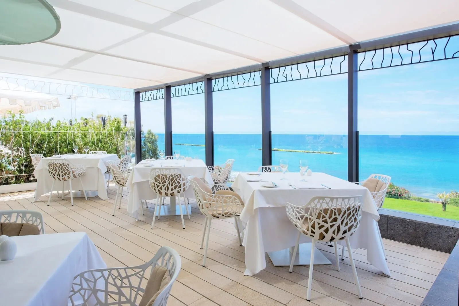 JOIA Salomé by Iberostar: A terrace with white tables and chairs, overlooking a coastal view