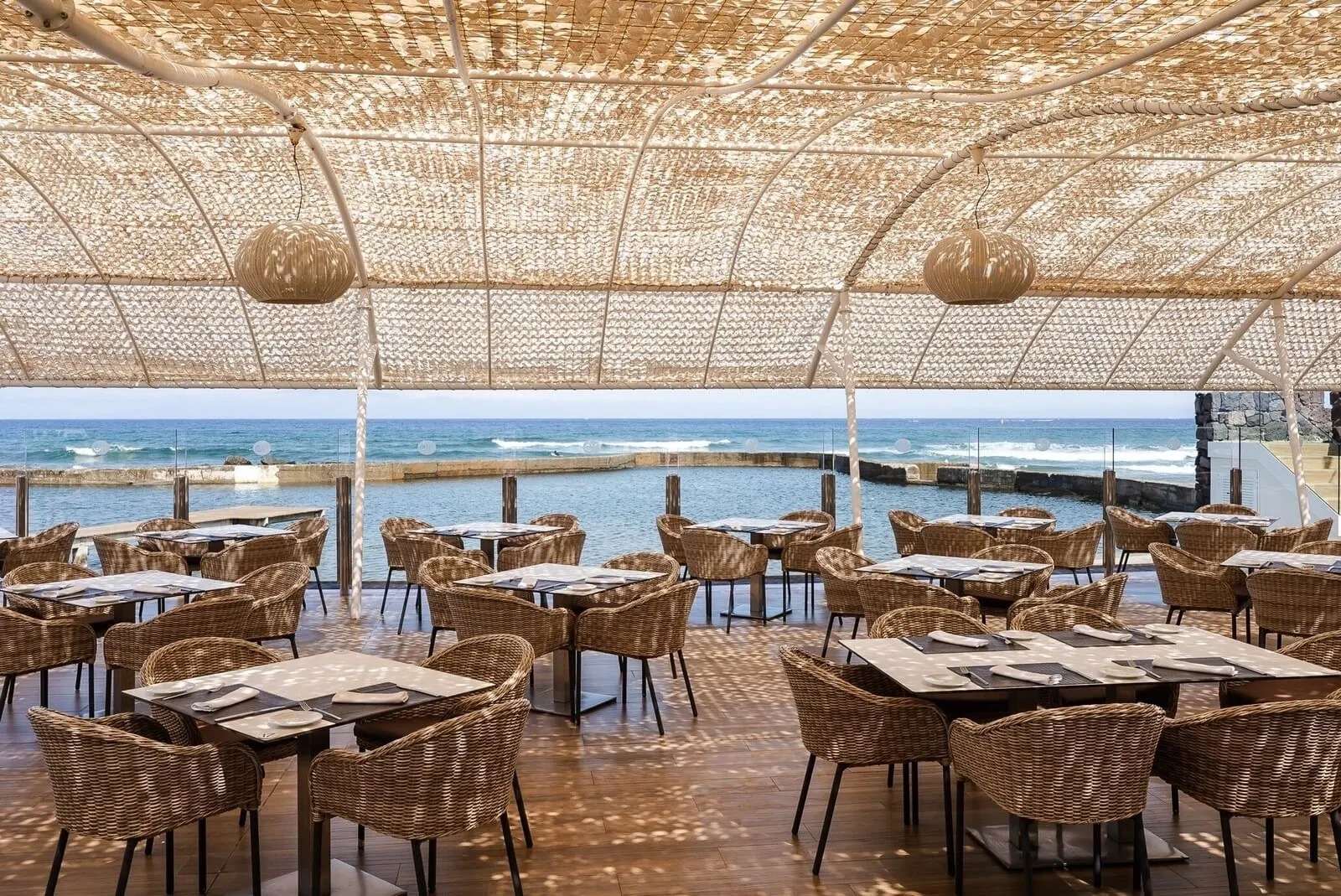 Europe Villa Cortés: An outdoor dining area with wicker furniture and a view of the ocean
