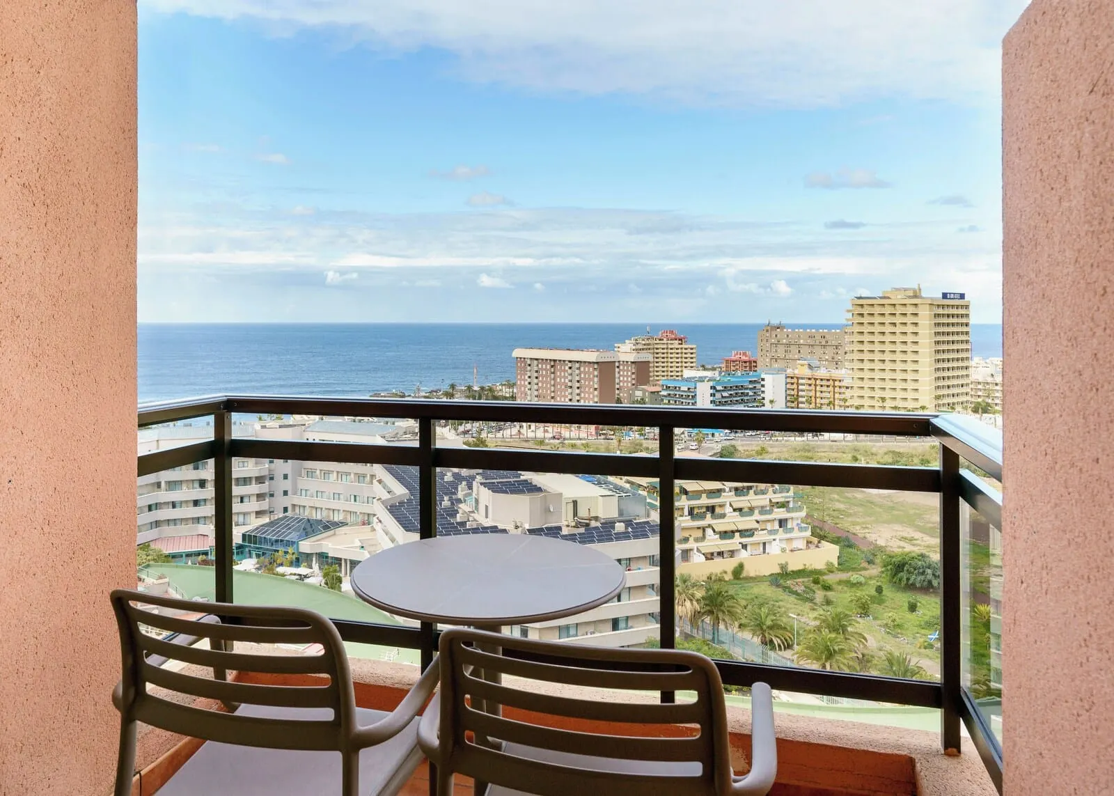 AluaSoul Orotava Valley: A balcony with a table and chairs, overlooking a cityscape with buildings and a beach