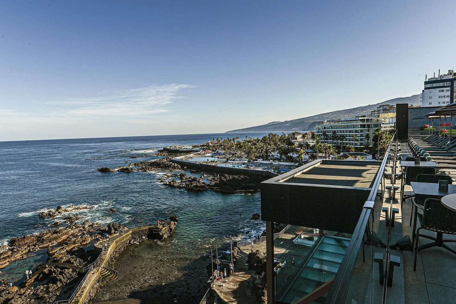 Silken Saaj Maar: A coastal hotel with outdoor seating overlooking the sea, a rocky shoreline