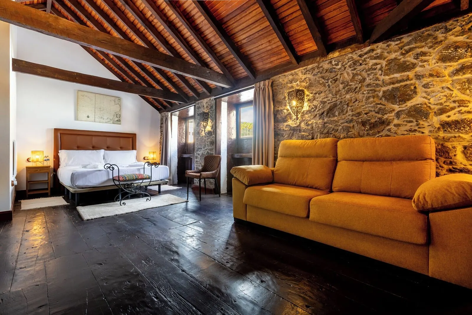 Hotel Duque de la Torre: A room with a bed, a sofa, a stone wall, and wooden beams