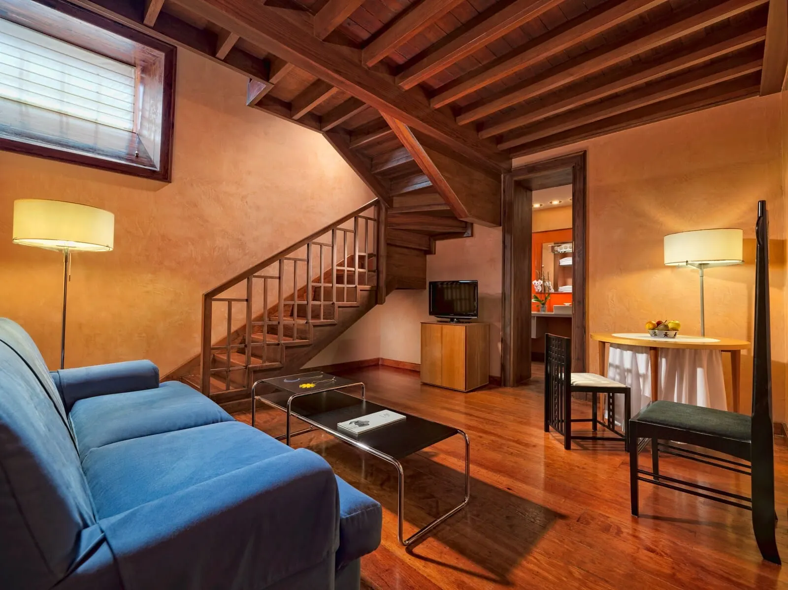 Hotel San Roque: A living room with a sofa, coffee table, TV, and a staircase