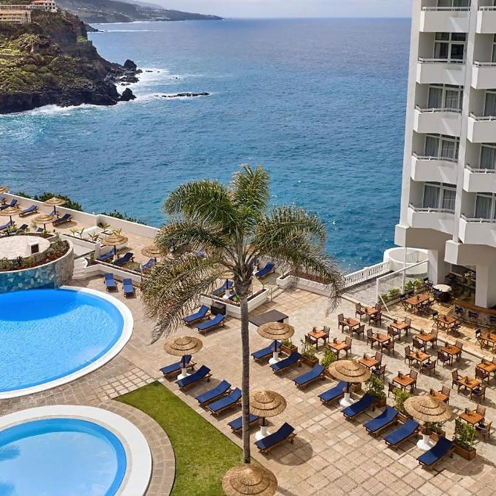 Precise Resort Tenerife: A resort with a pool area, lounge chairs, and a view of the ocean