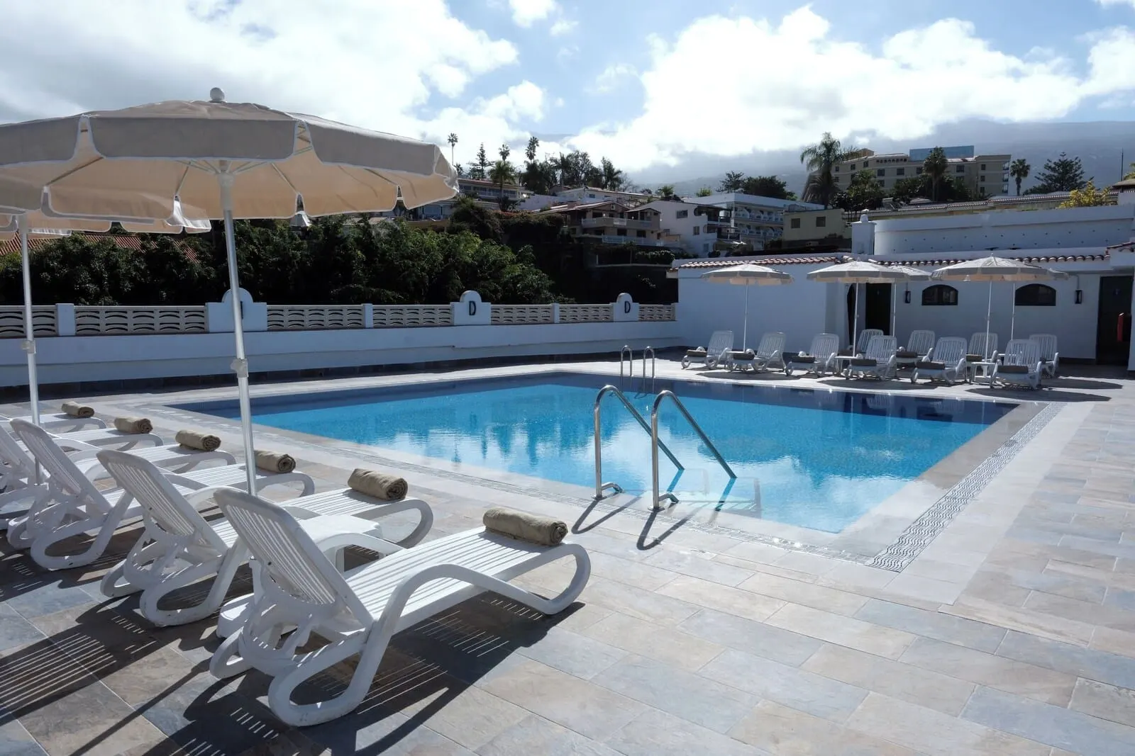 Muthu La Perla Tenerife: A swimming pool with lounge chairs and umbrellas