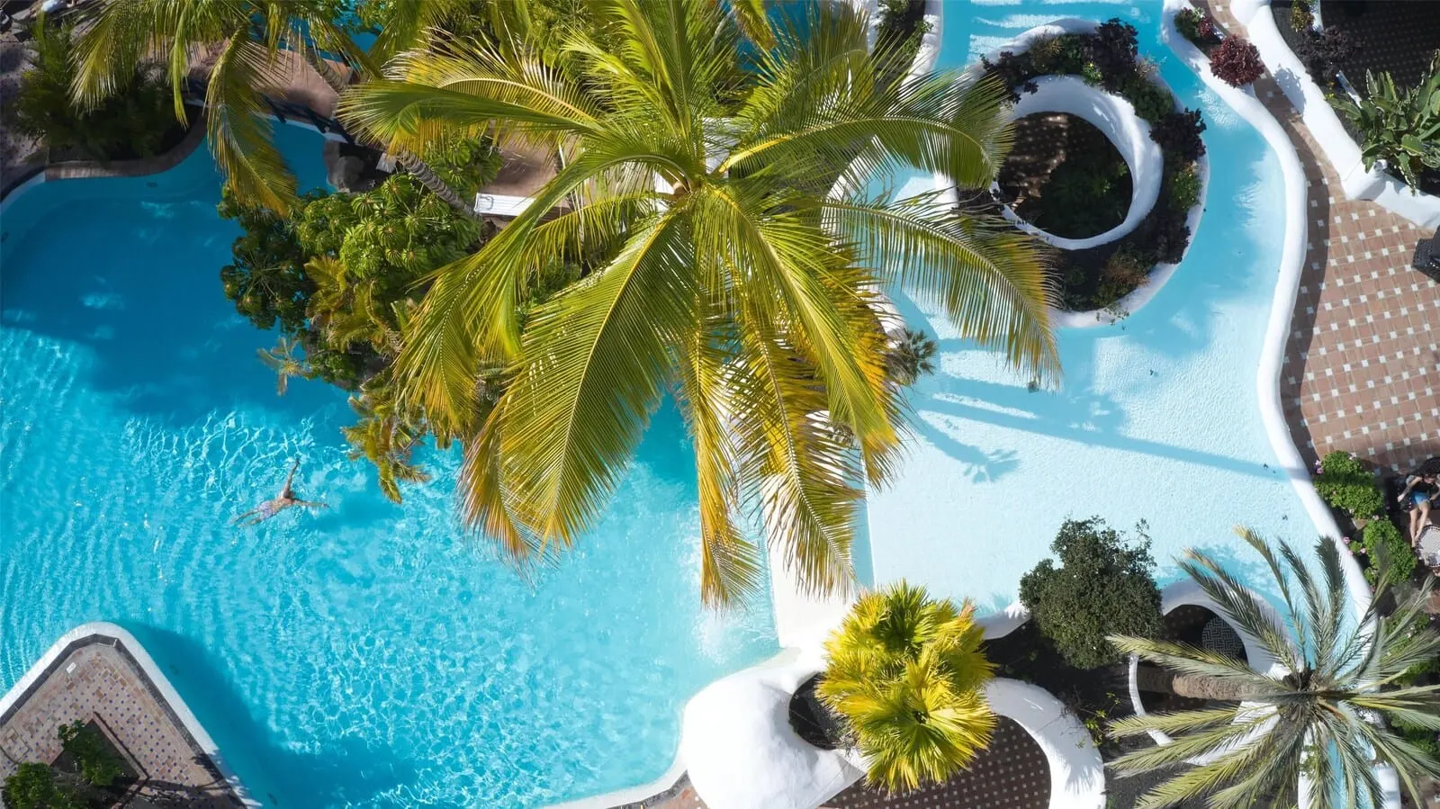 Hyatt Ziva Jardín Tropical Tenerife: An aerial view of a resort with a large swimming pool surrounded by palm trees and