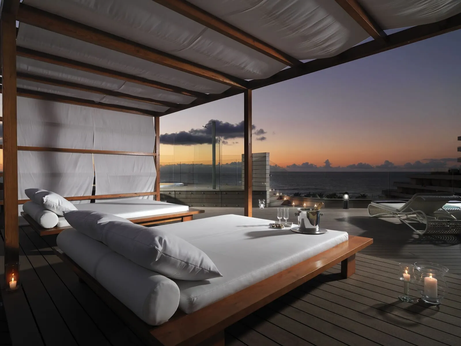 H10 Conquistador: A modern bedroom with a large bed, a wooden floor, and a view of the ocean at sunset