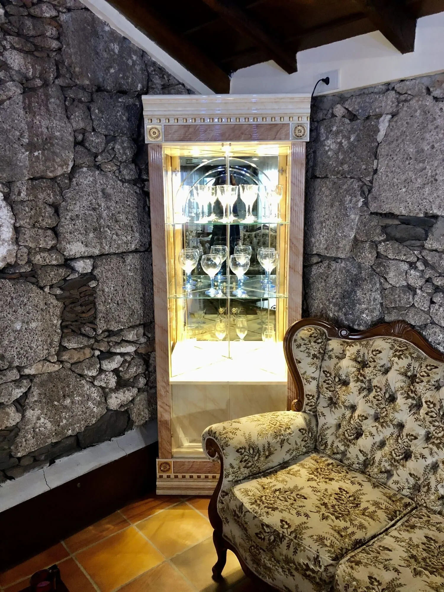 Hotel Rural Vilaflor: A room with a stone wall, a glass display cabinet with wine glasses