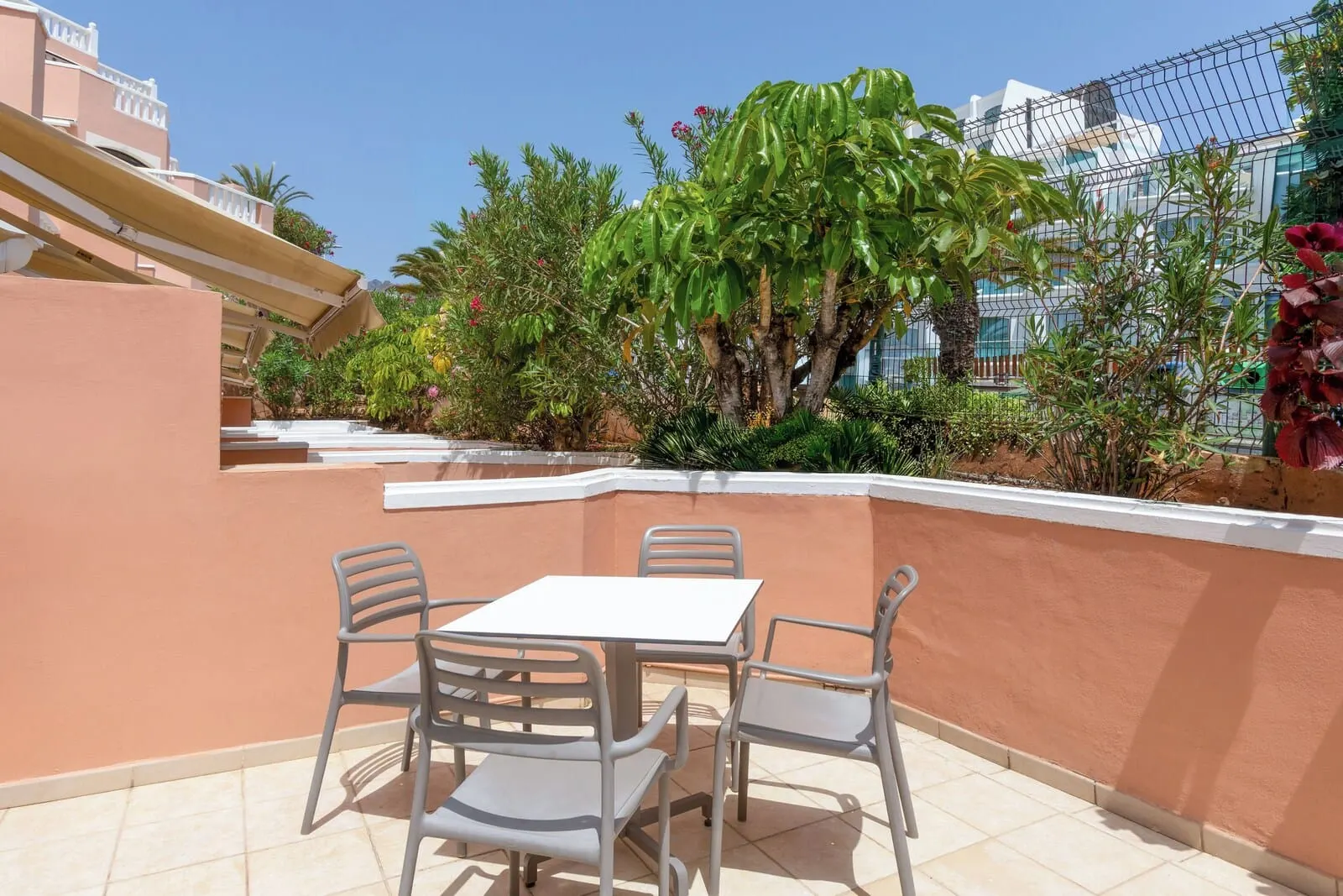 Sol Sun Beach Apartamentos: An outdoor patio with a table and chairs, surrounded by plants and a fence