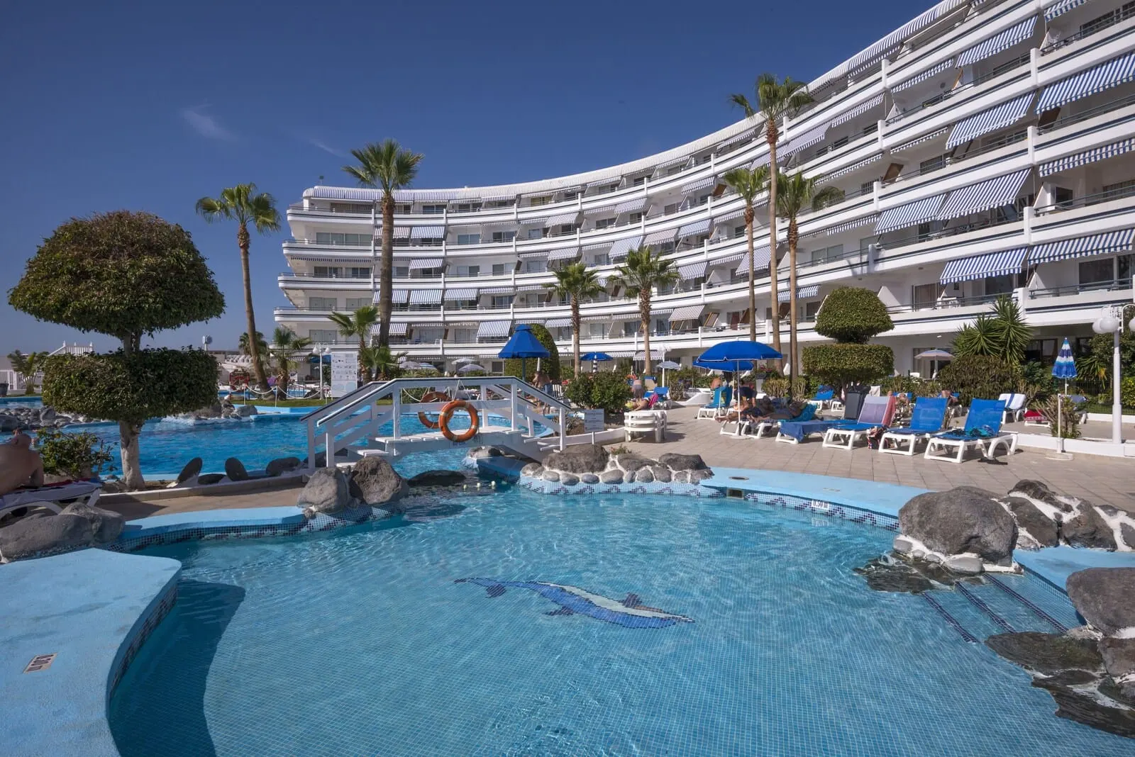 HOVIMA Atlantis: A hotel with a swimming pool, palm trees, and lounge chairs