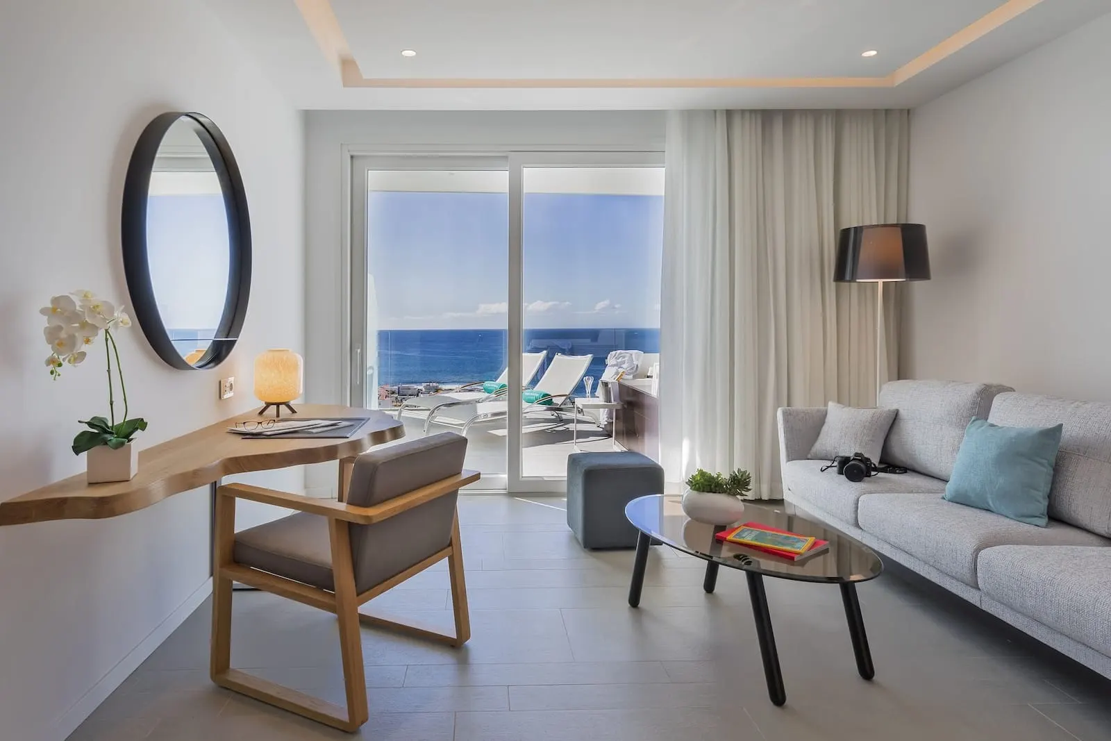 Royal Hideaway Corales Beach: A modern hotel room with a balcony, a sofa, a desk, and a chair