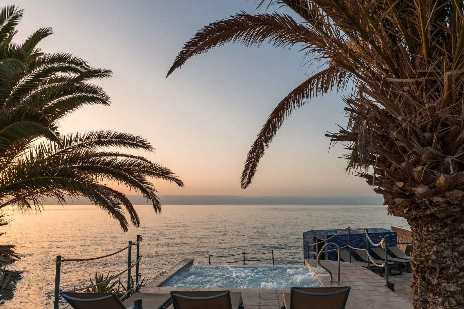 Catalonia Punta del Rey: A pool area with a view of the sea, palm trees, and a clear sky