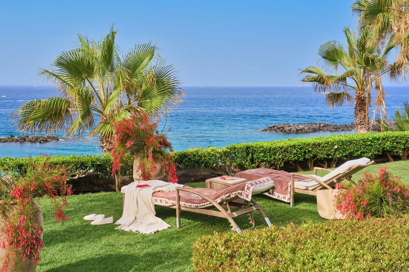 JOIA El Mirador by Iberostar: A seaside garden with lounge chairs, a palm tree, and a view of the ocean