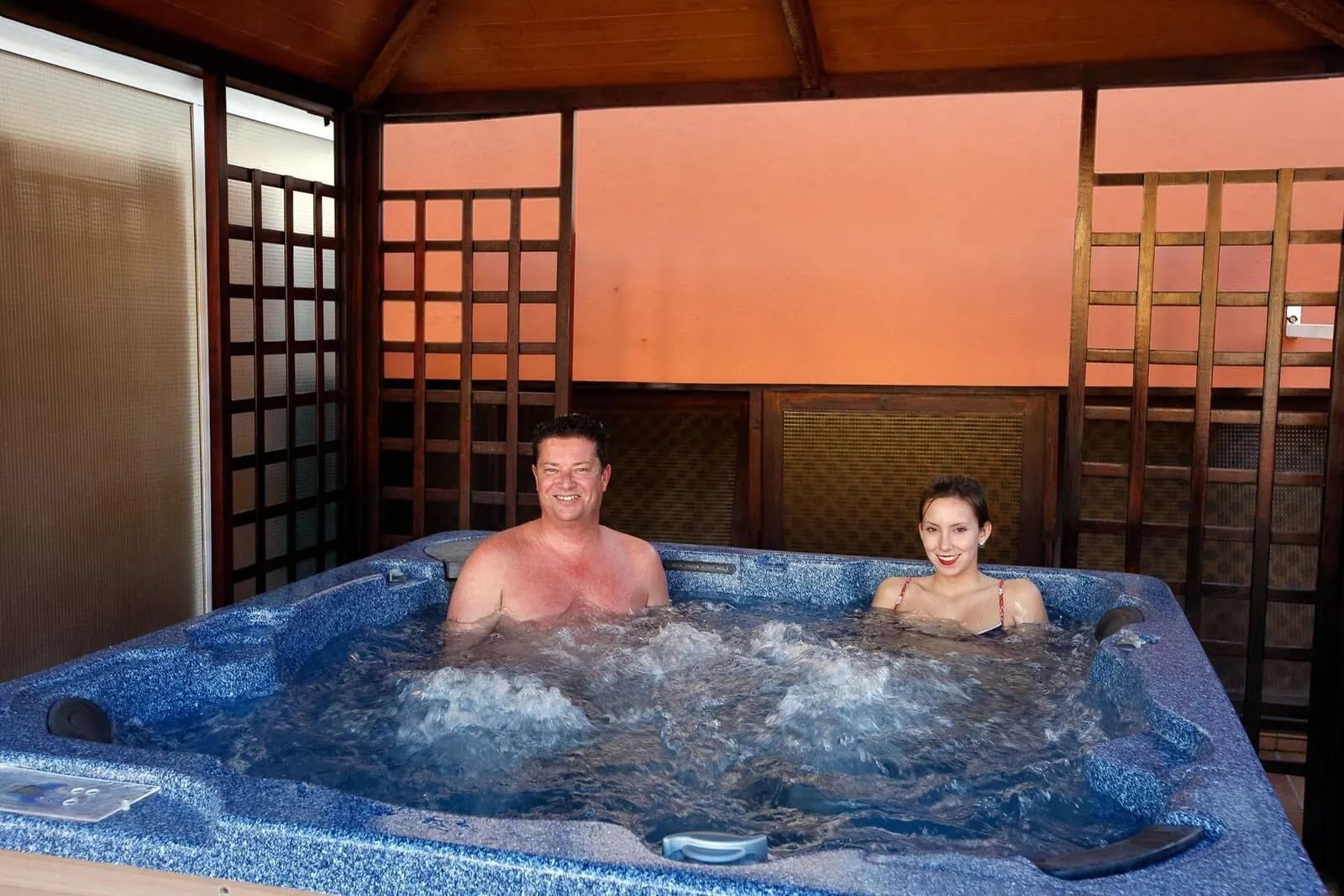 Hotel Monopol: A hot tub with two people inside, surrounded by wooden lattice panels and a tiled floor