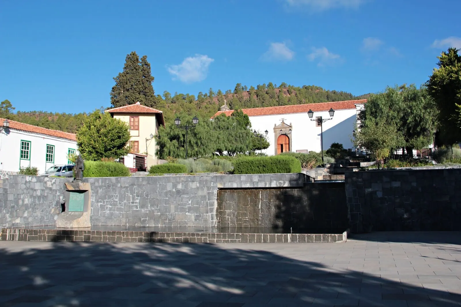 Hotel Rural Vilaflor: A stone wall with a statue, a building with a red roof