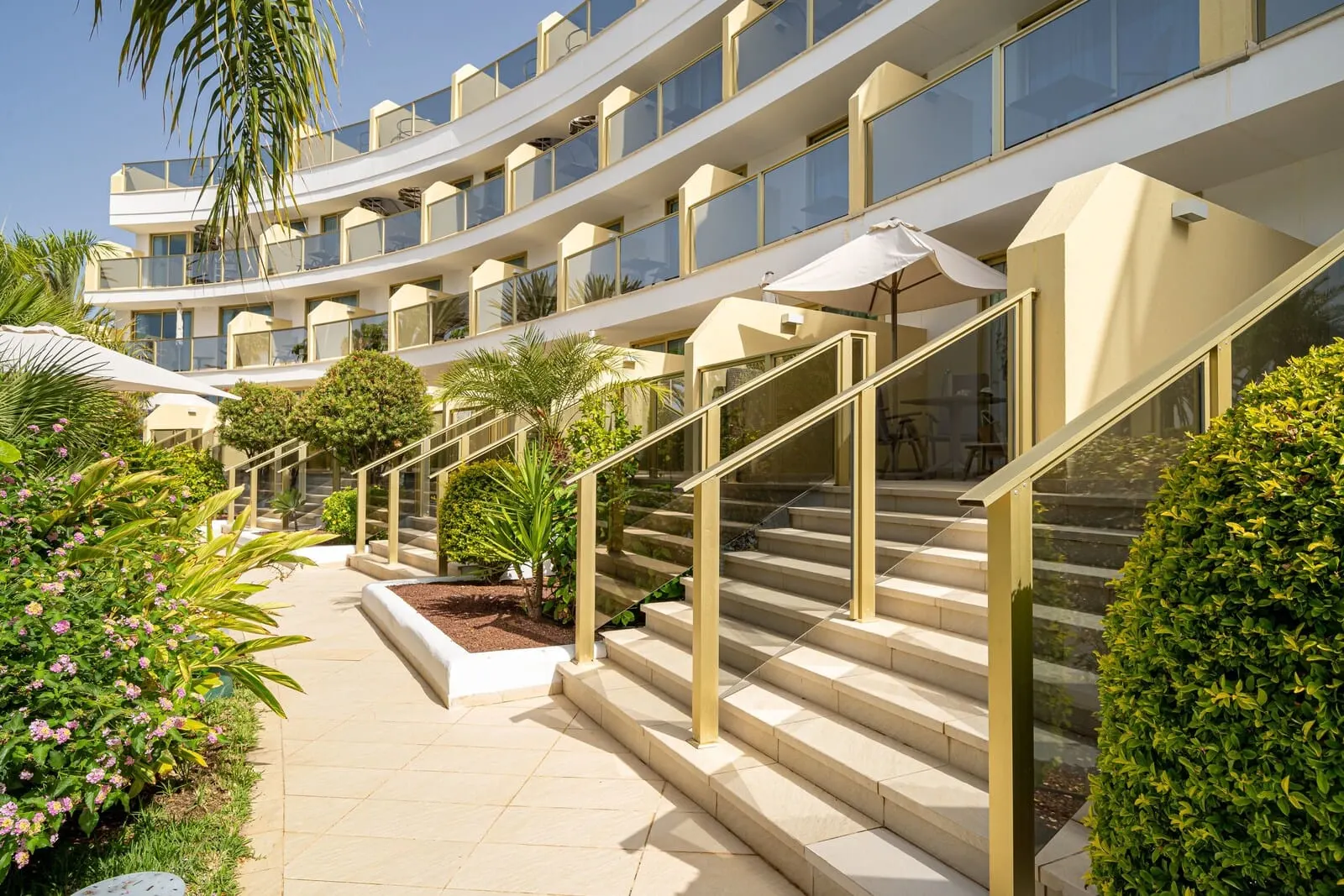 Sir Anthony: A multi-level hotel with outdoor stairs, palm trees, and a clear sky