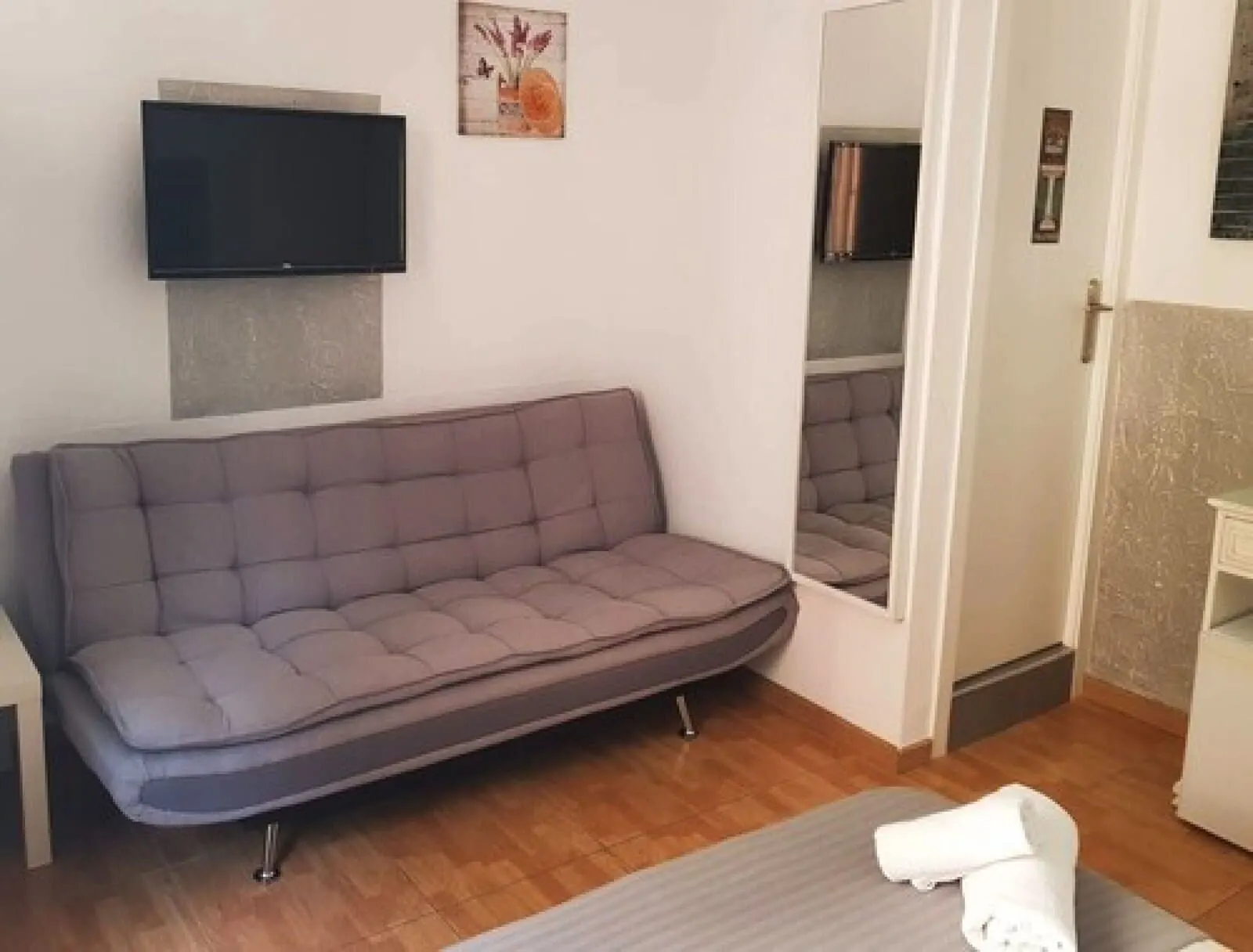 Nuevo Hotel Horizonte: A modern room with a grey sofa, a flat-screen TV mounted on the wall