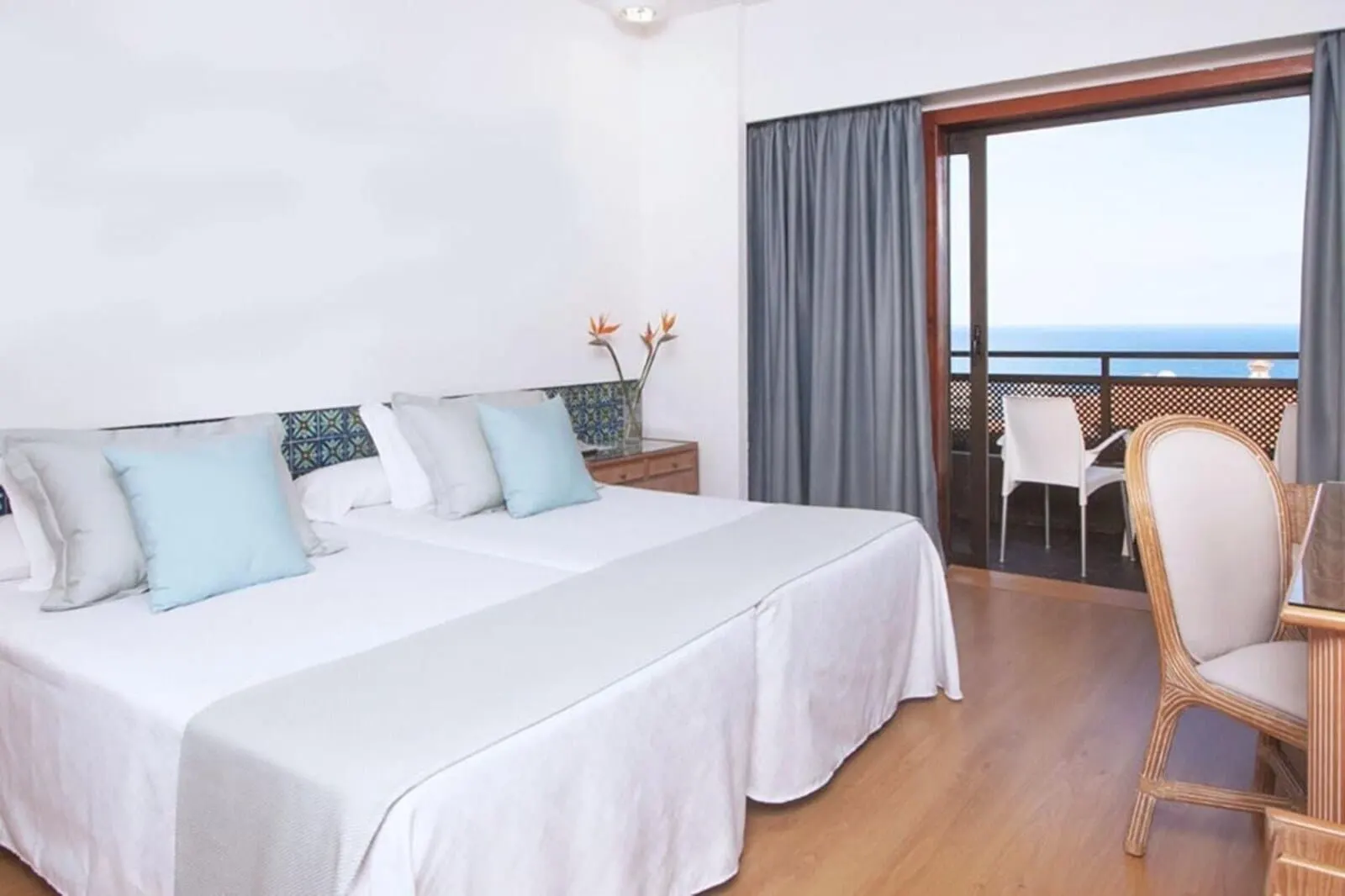FERGUS Puerto de la Cruz: A hotel room with two beds, a balcony with a view, and a dining area with a chair