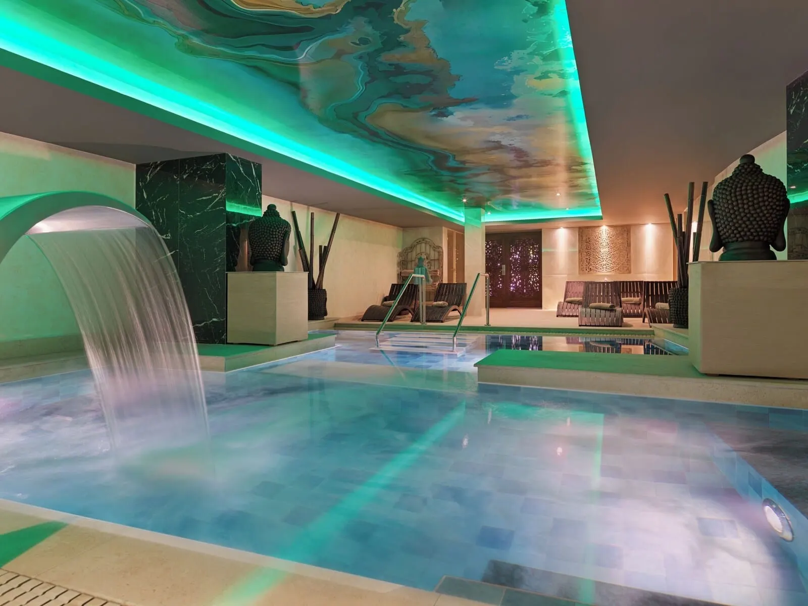 Gran Oasis Resort: A modern indoor pool area with a waterfall feature, seating, and a decorative ceiling