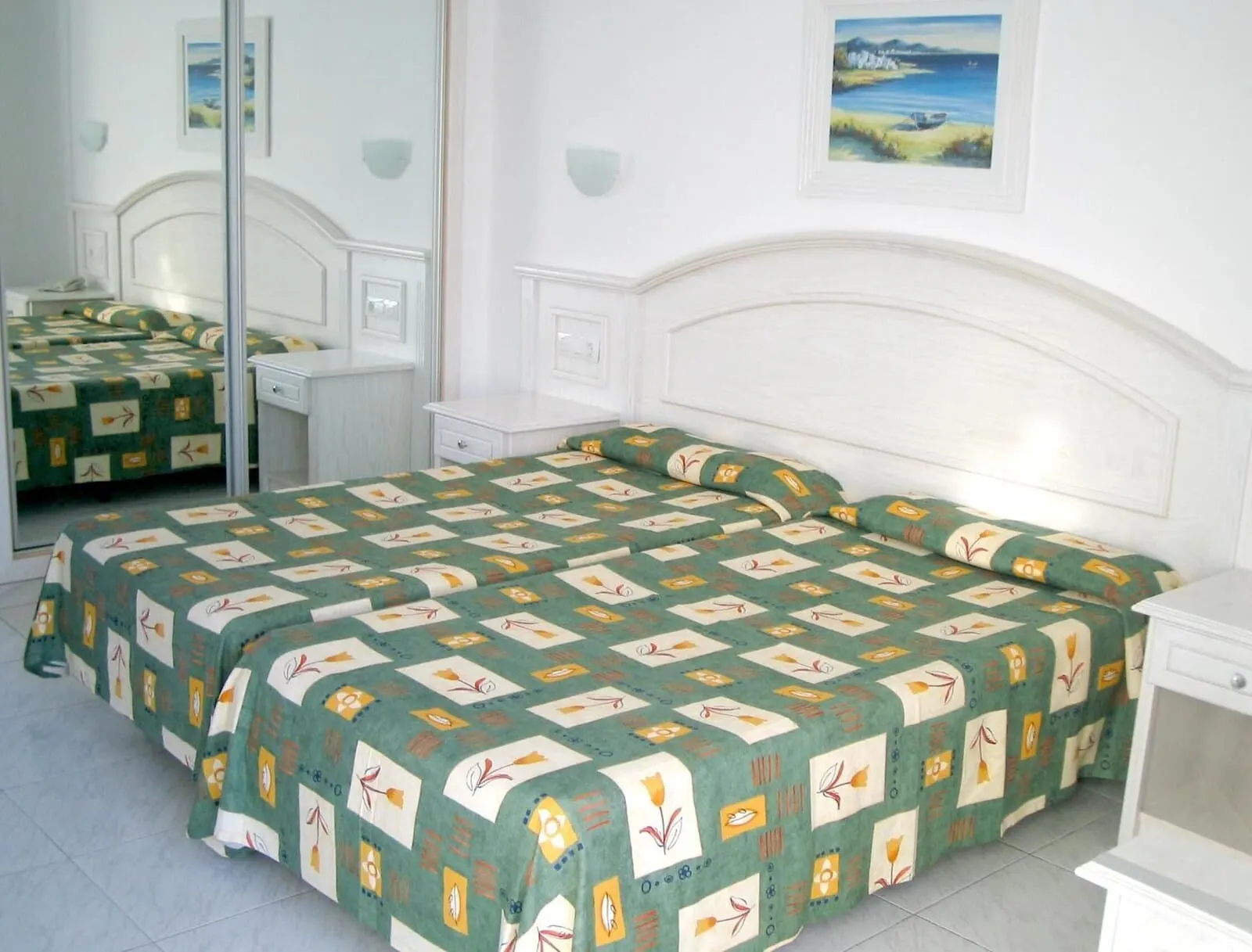 Apartamentos La Carabela: A bedroom with a large bed, two bedside tables, a nightstand, a mirror