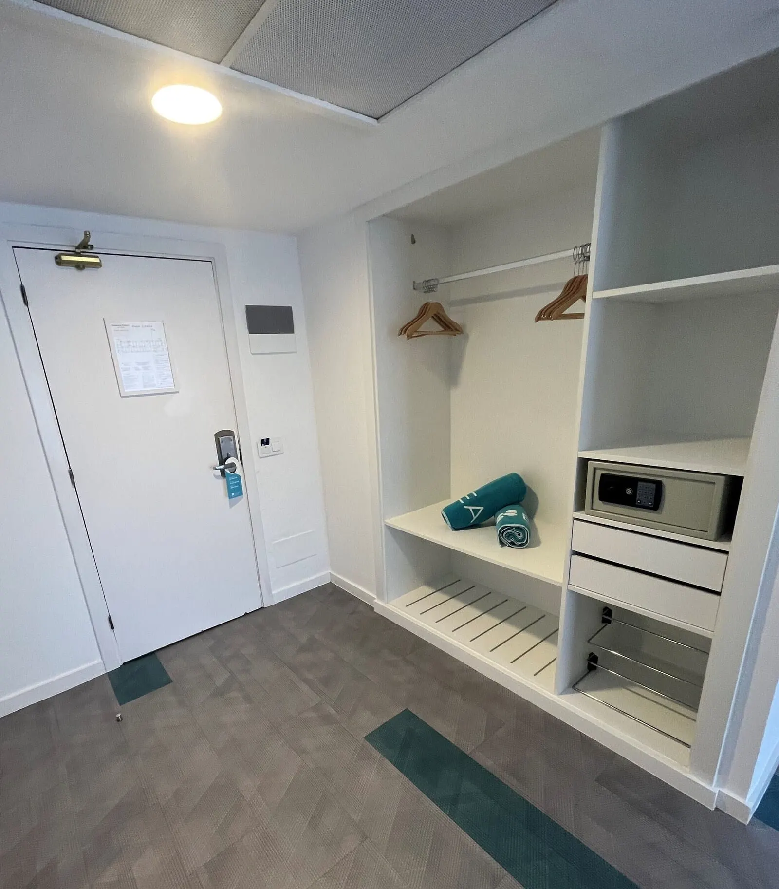 BLUESEA Puerto Resort: A room with a white door, a coat rack, a shelf with a teal towel, and a control panel