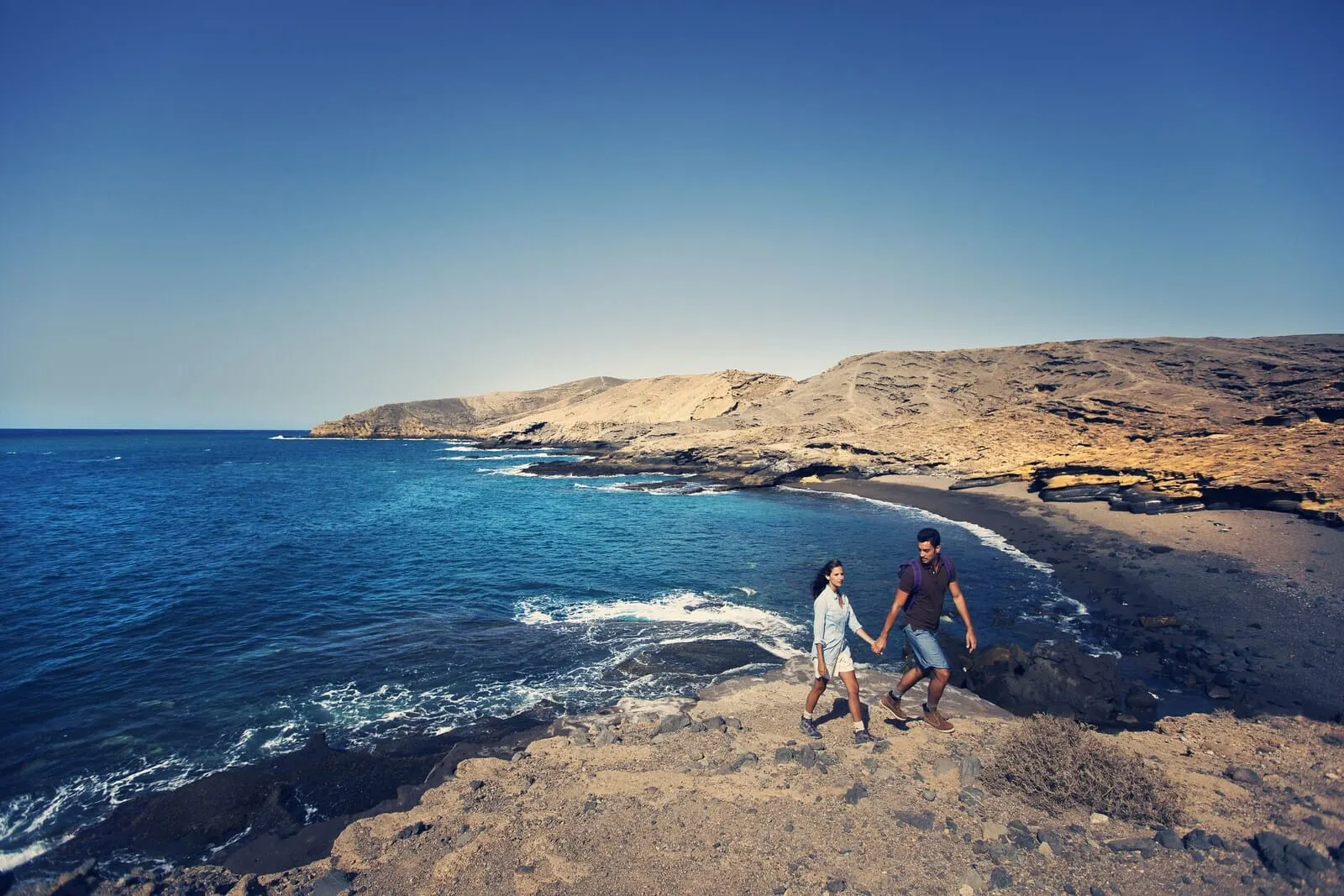 Hotel Rural Finca Salamanca: A rocky beach with clear blue water and a mountainous backdrop