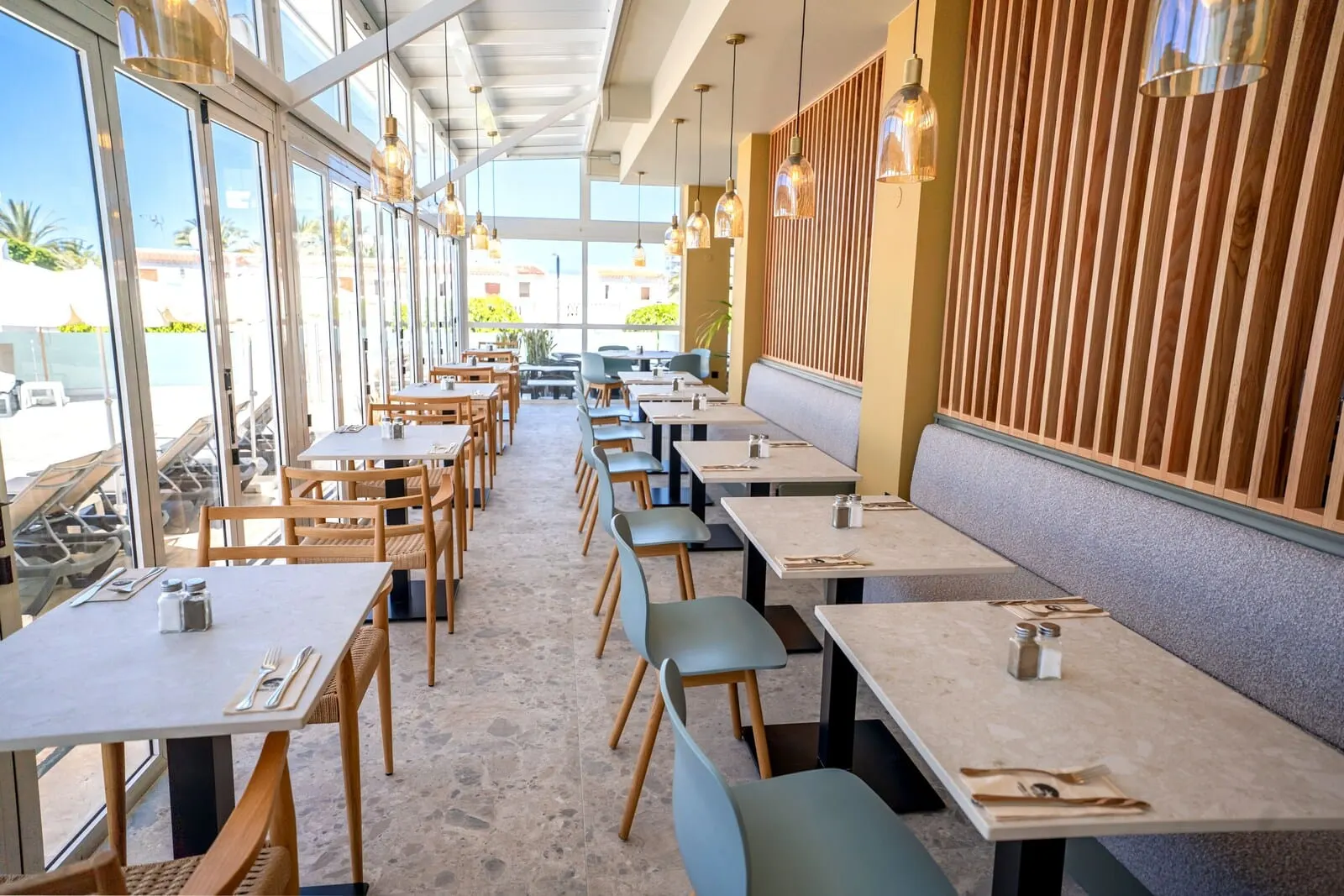 Coral Ocean View: A restaurant with multiple tables and chairs, large windows, and a wooden wall panel