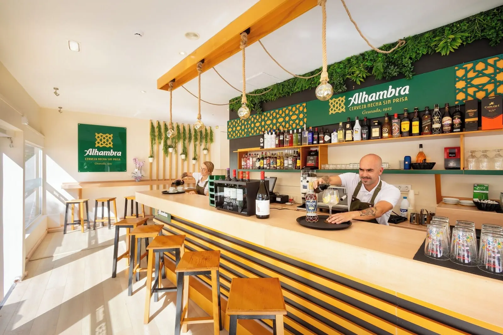 Hotel Boutique HC Maga: A bar area with a counter, stools, and a variety of bottles and glasses
