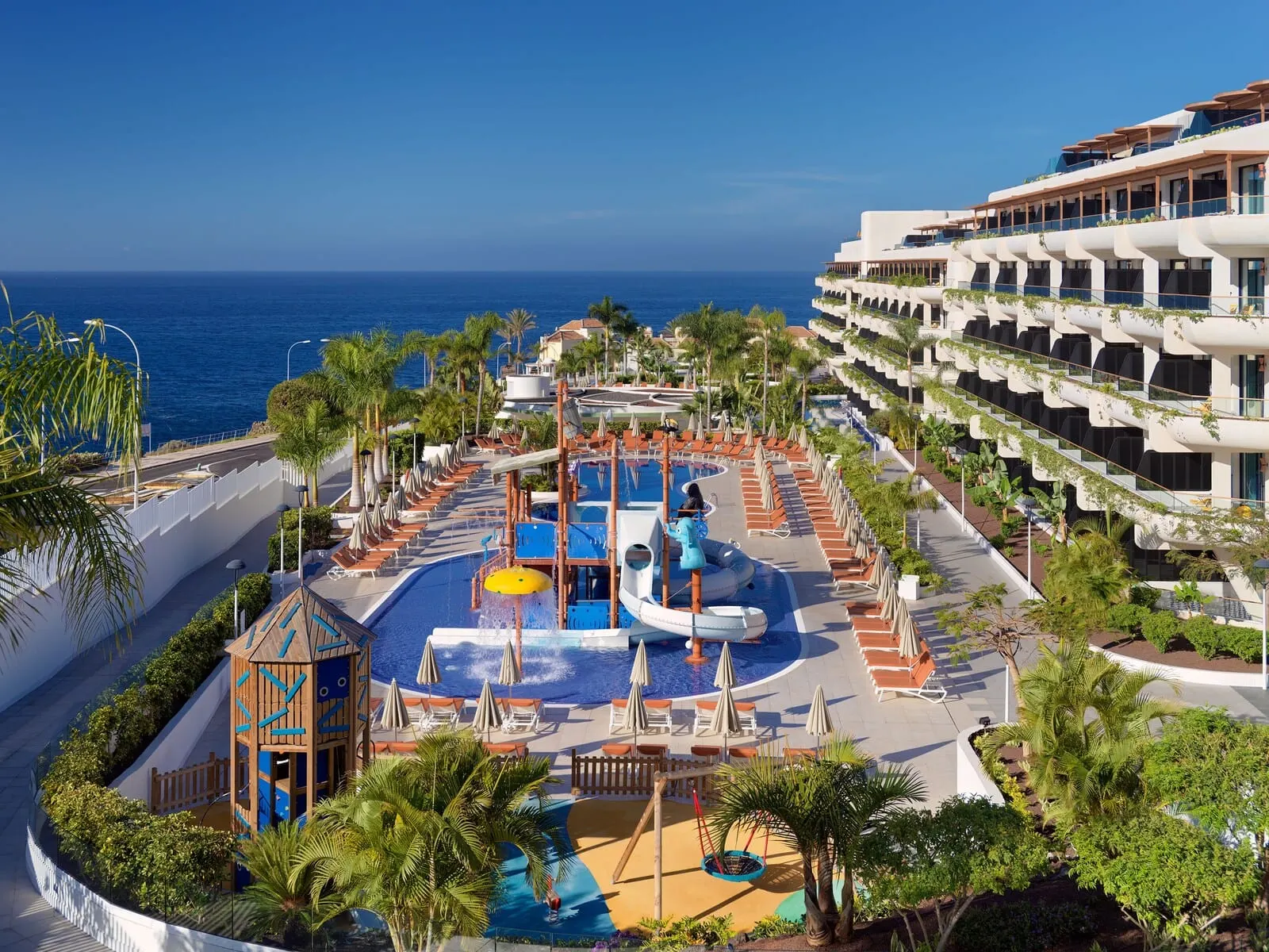 H10 Atlantic Sunset: A resort pool area with a water slide, lounge chairs, and a view of the ocean
