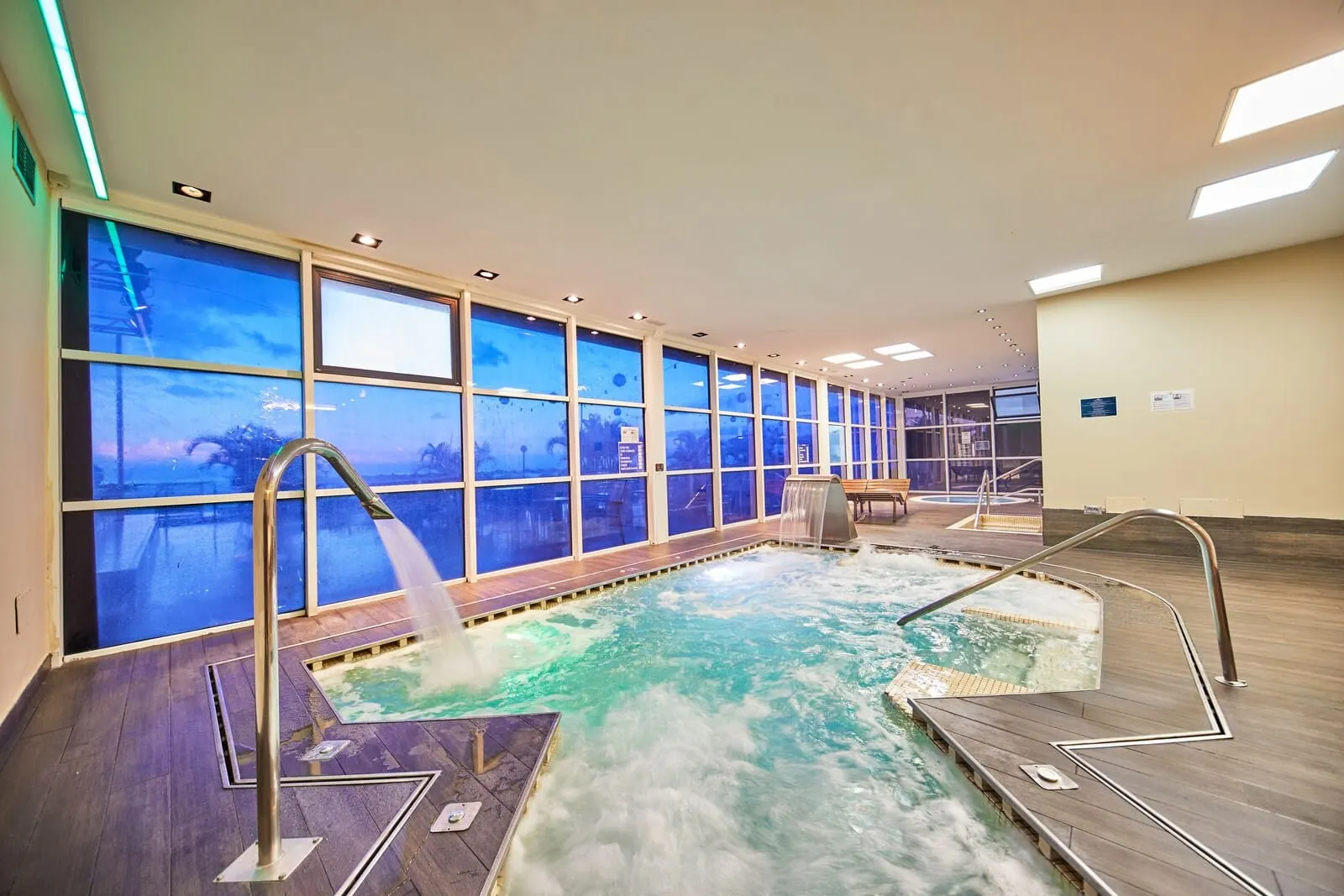 TUI Blue Los Gigantes: A large indoor swimming pool with clear windows, metal railings, and a wooden deck