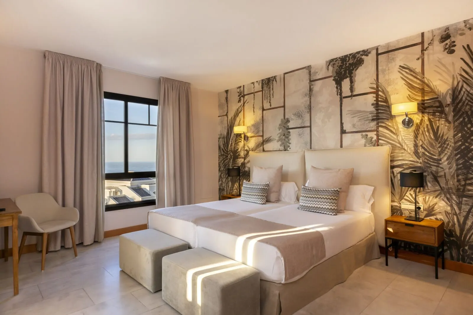 Hotel Suite Villa María: A modern hotel room with a large bed, a desk, and a view of the city