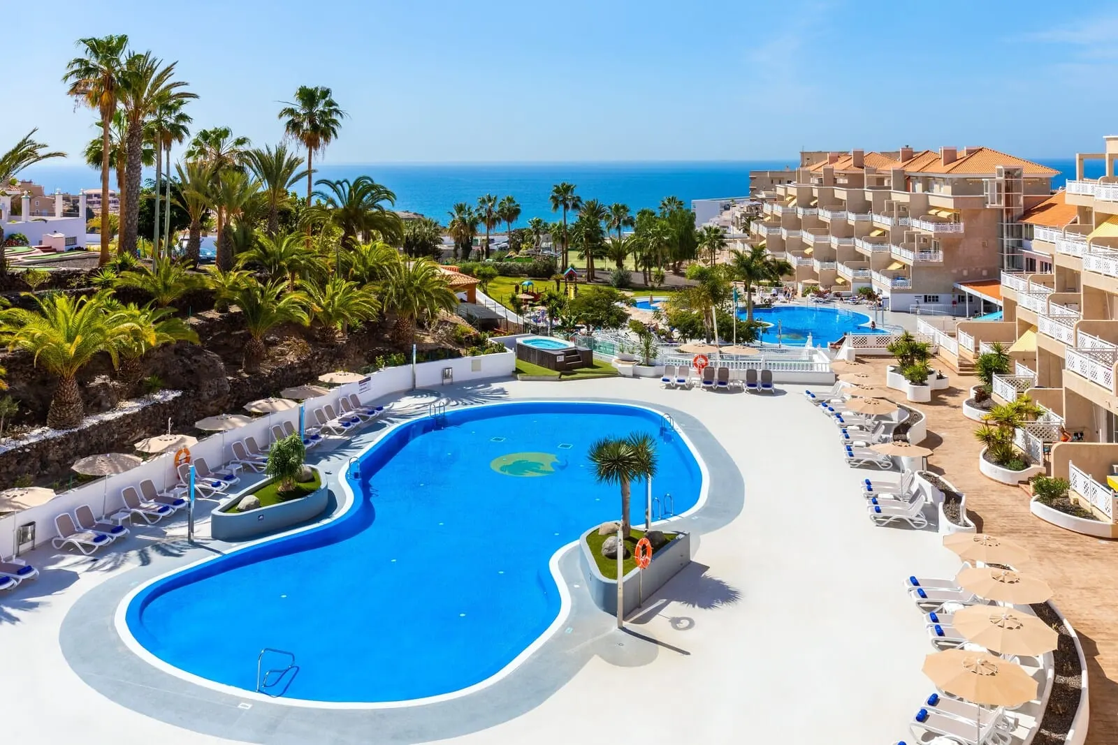 Hotel Tropical Park: A resort with a large pool, palm trees, and a view of the ocean