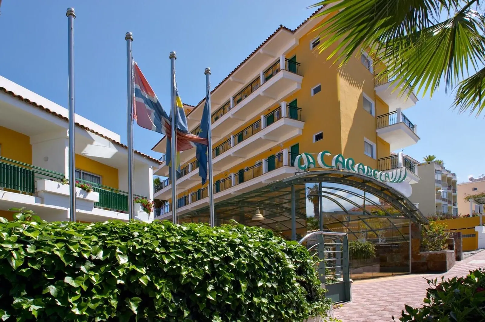 Apartamentos La Carabela: A hotel with a yellow facade, multiple balconies, and a covered entrance