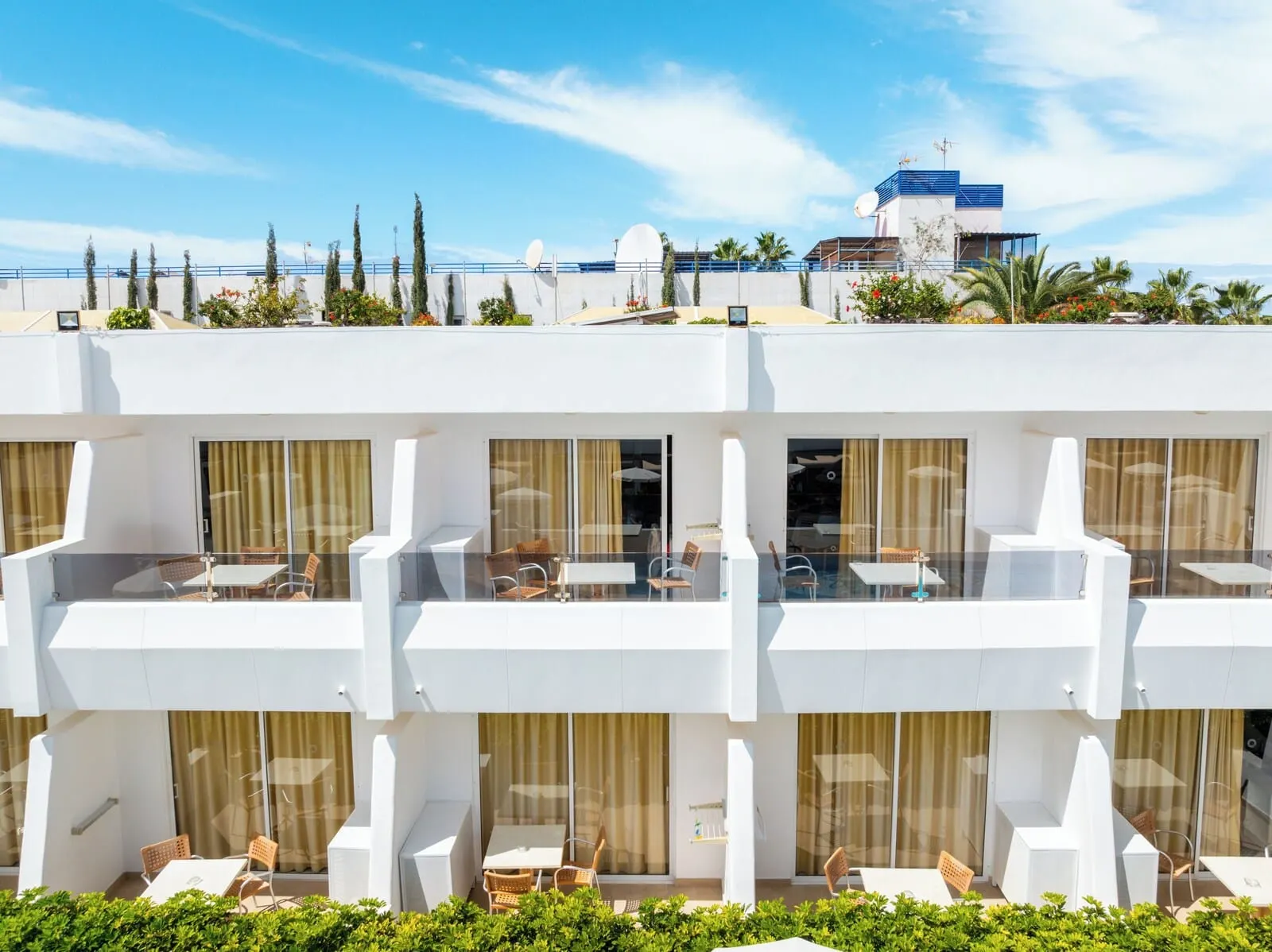 HOVIMA Panorama: A modern hotel with multiple balconies, outdoor seating areas, and a view of the sea