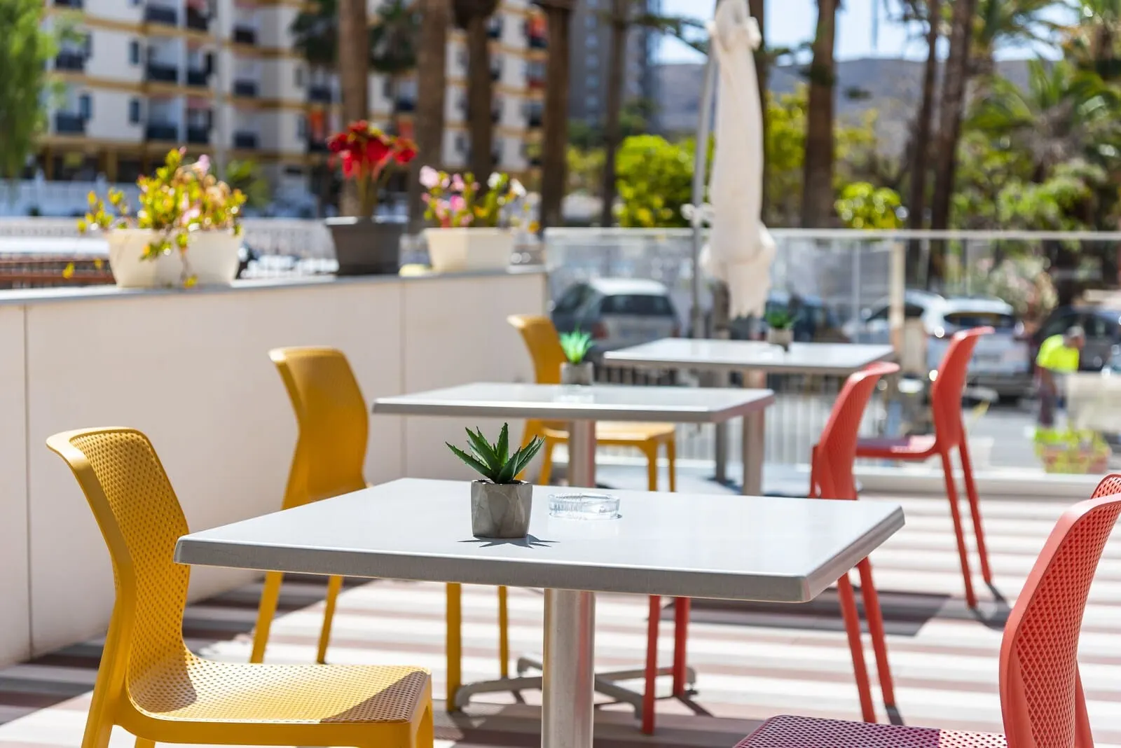Andrea's Hotel Tenerife: An outdoor seating area with yellow and red chairs, white tables, and potted plants