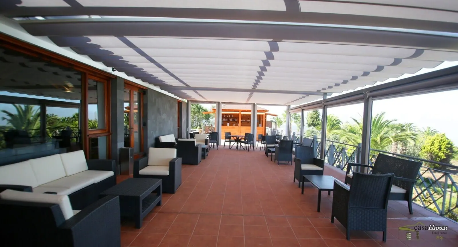 Hotel Rural Casablanca: A covered outdoor patio with seating, a bar area, and views of palm trees