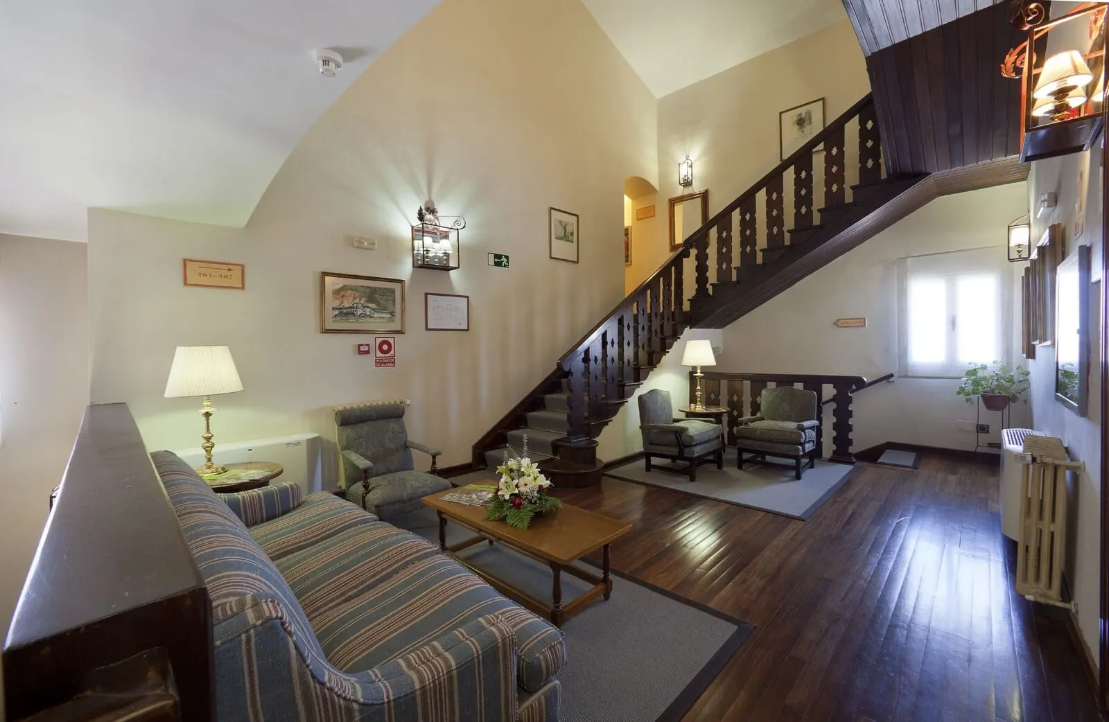 Parador de Las Cañadas del Teide: A spacious living room with a wooden staircase, a sofa, a coffee table with flowers