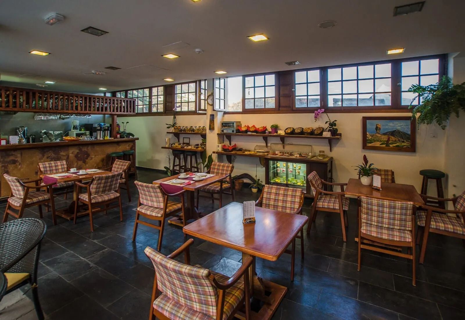 Garahotel: A restaurant with wooden tables and chairs, a bar area, and large windows with a view