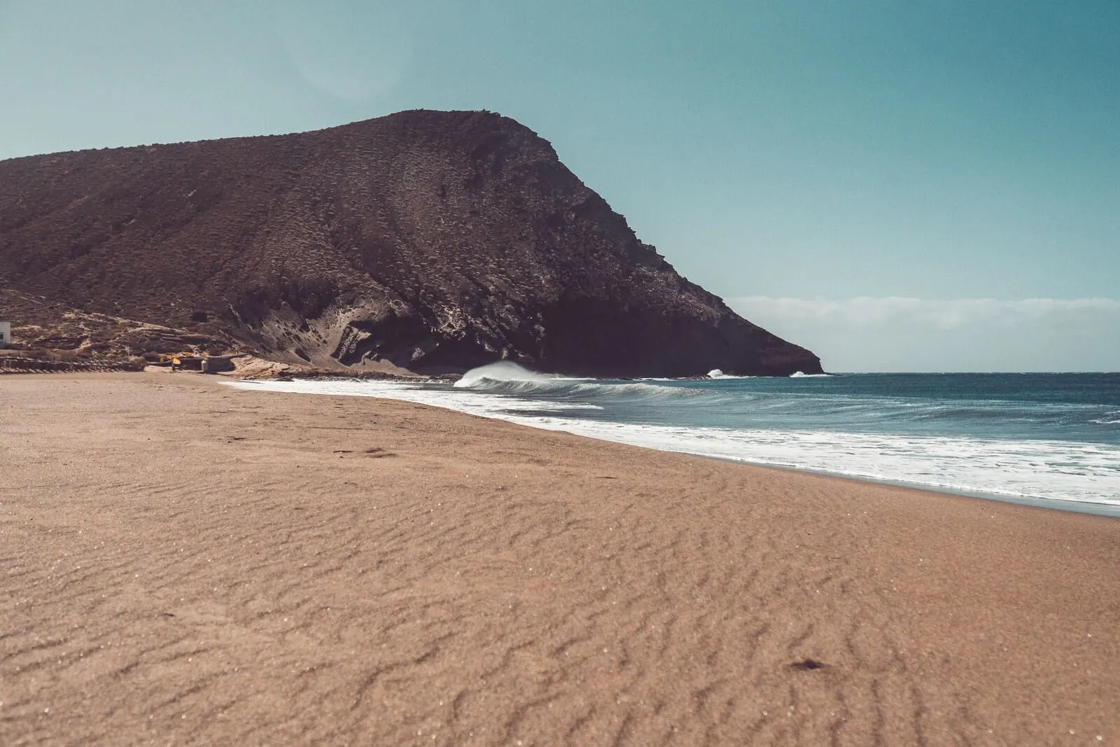 Hotel Ventus: A beach with a large mountain in the background and waves crashing onto the shore