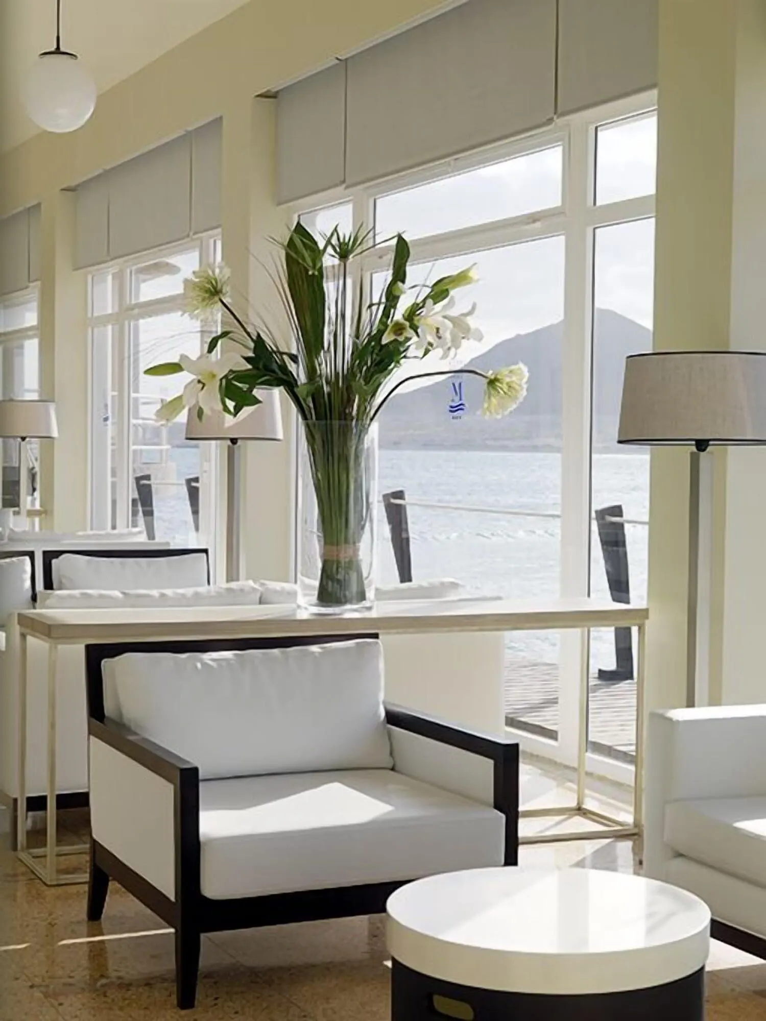 Médano Hotel: A modern room with a large window overlooking a body of water, a white sofa