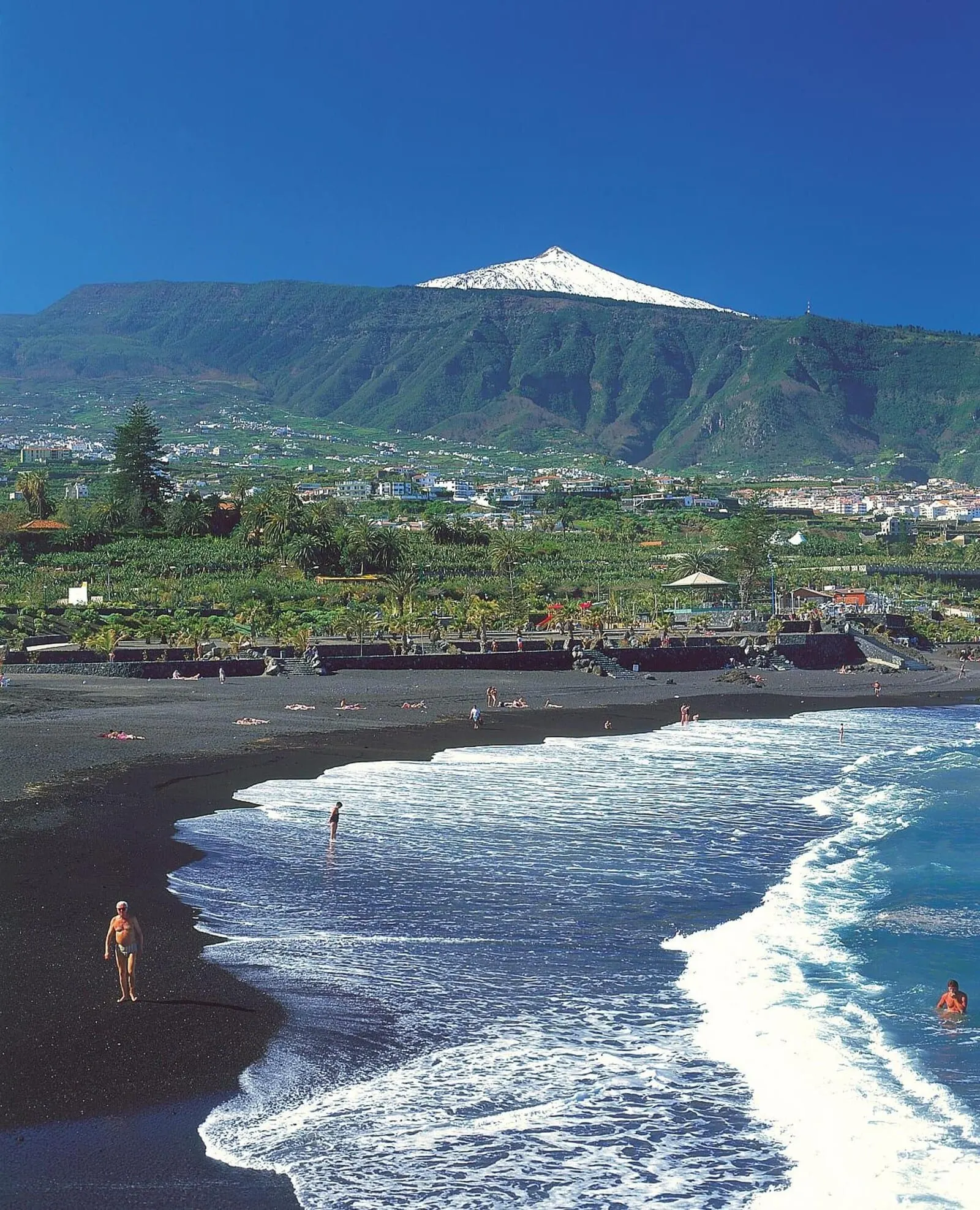 Hotel Don Manolito: A beach with waves, a mountain in the background, and a town across the water