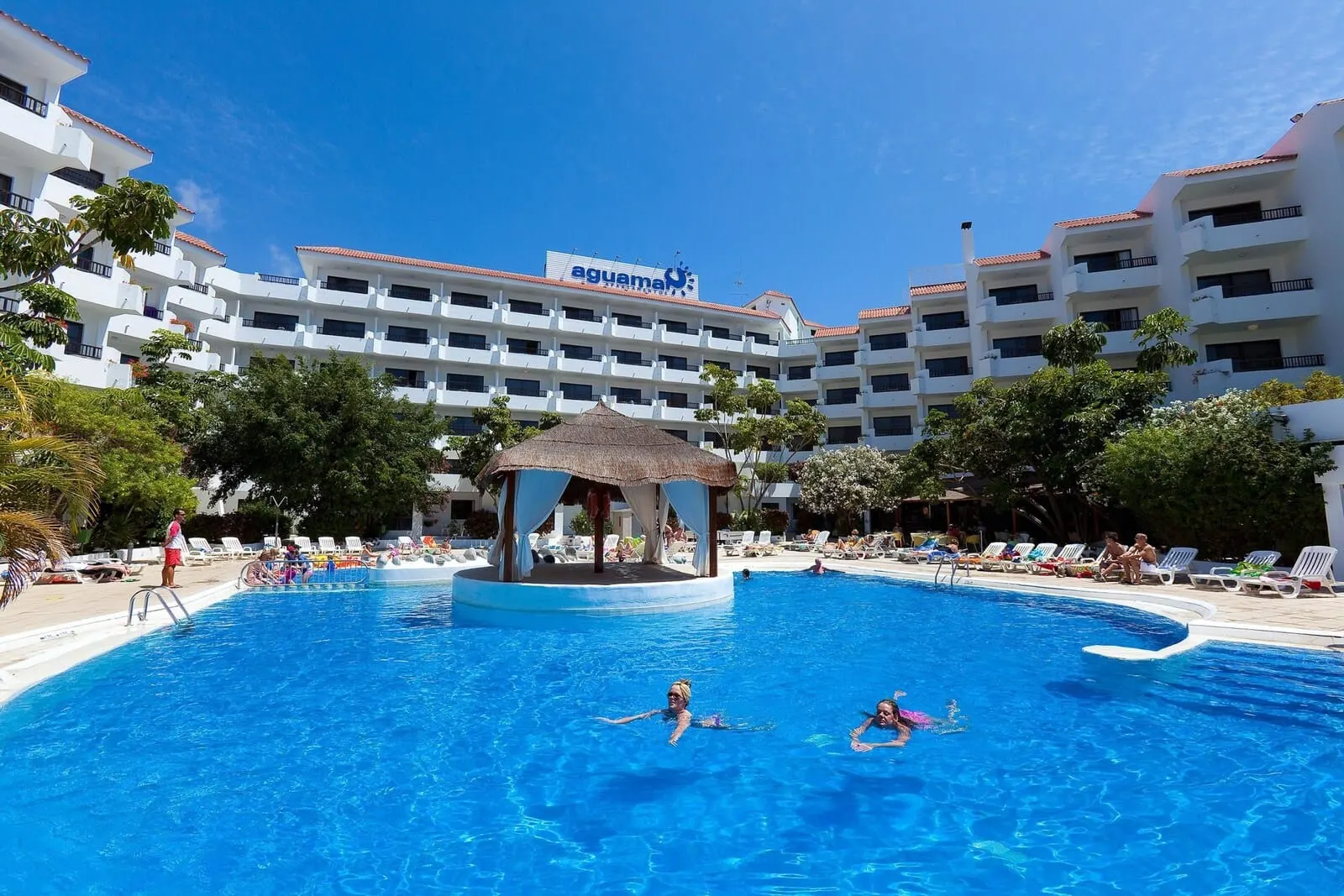 Apartamentos Aguamar: A swimming pool with a gazebo, surrounded by lounge chairs and palm trees