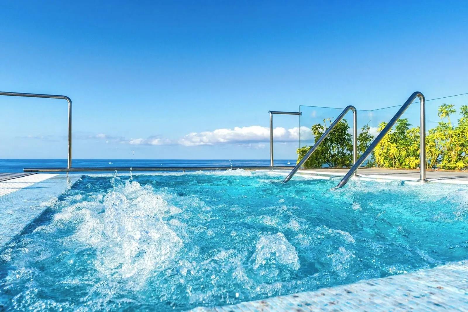 Arona Gran Hotel: A clear blue pool with metal railings, surrounded by a tiled deck and palm trees