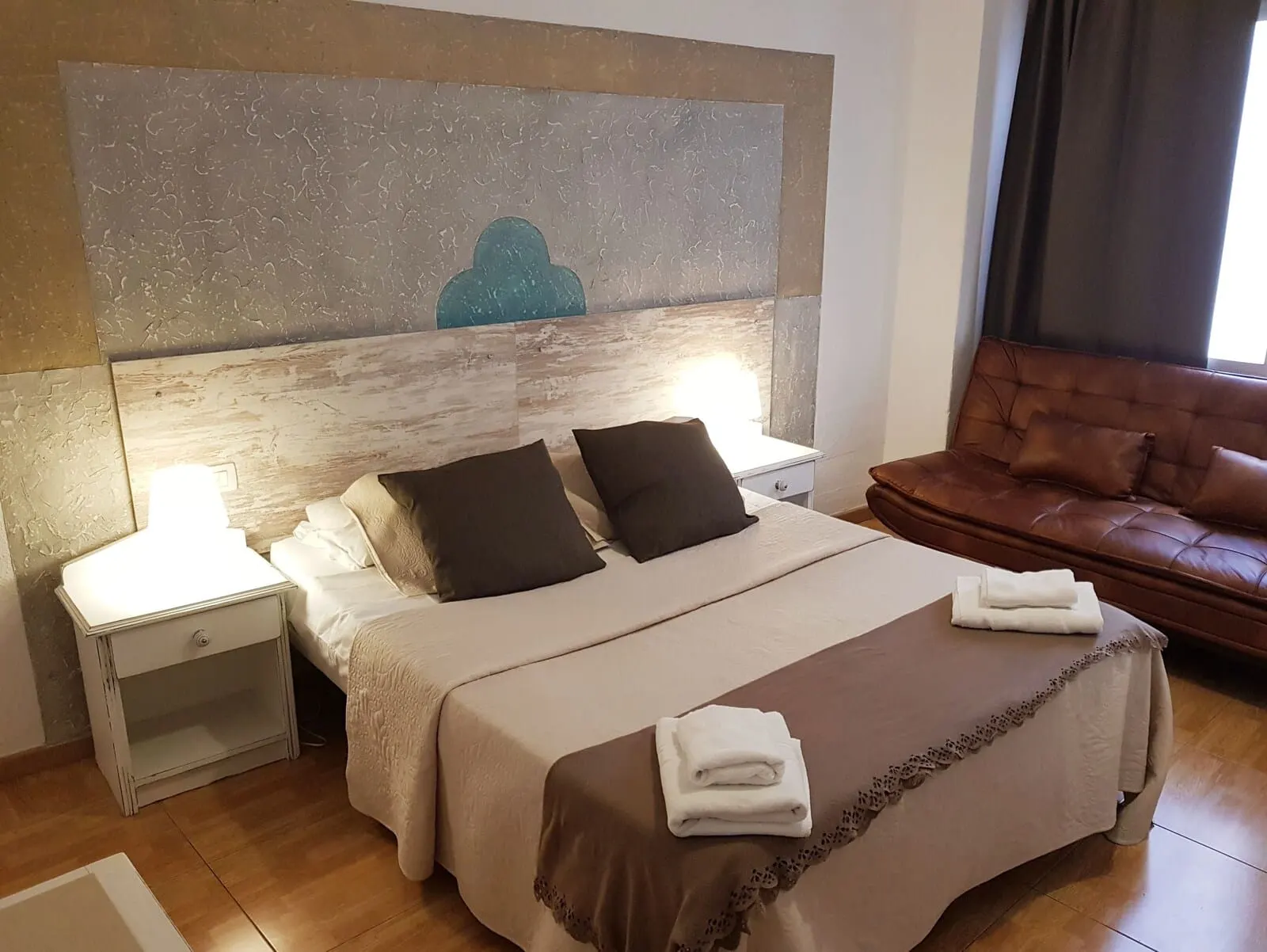 Nuevo Hotel Horizonte: A hotel room with a bed, two bedside tables, a brown leather sofa