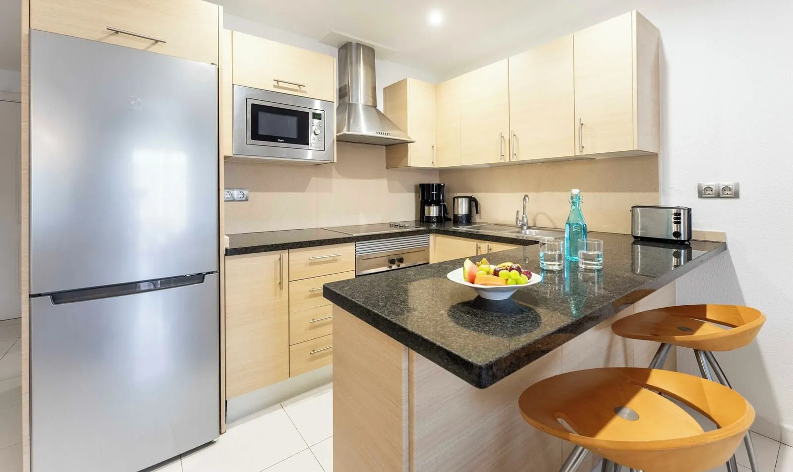 Ona Hollywood Mirage: A modern kitchen with stainless steel appliances, wooden cabinets, a granite countertop