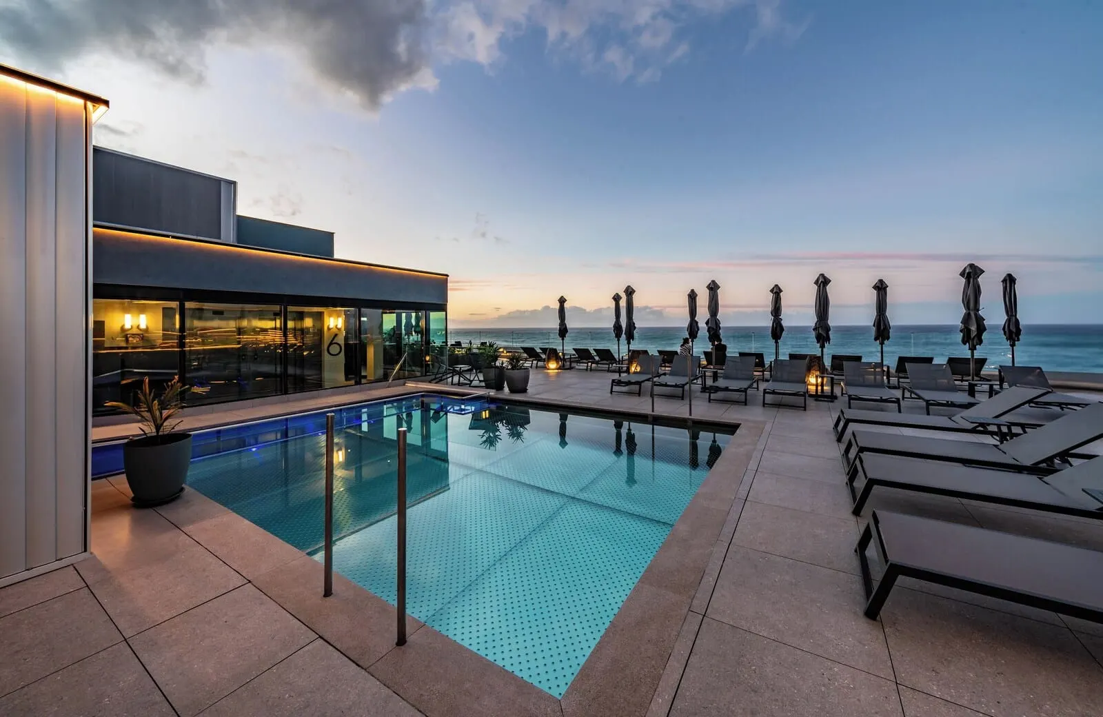 Silken Saaj Maar: A rooftop pool with lounge chairs and umbrellas, overlooking the ocean
