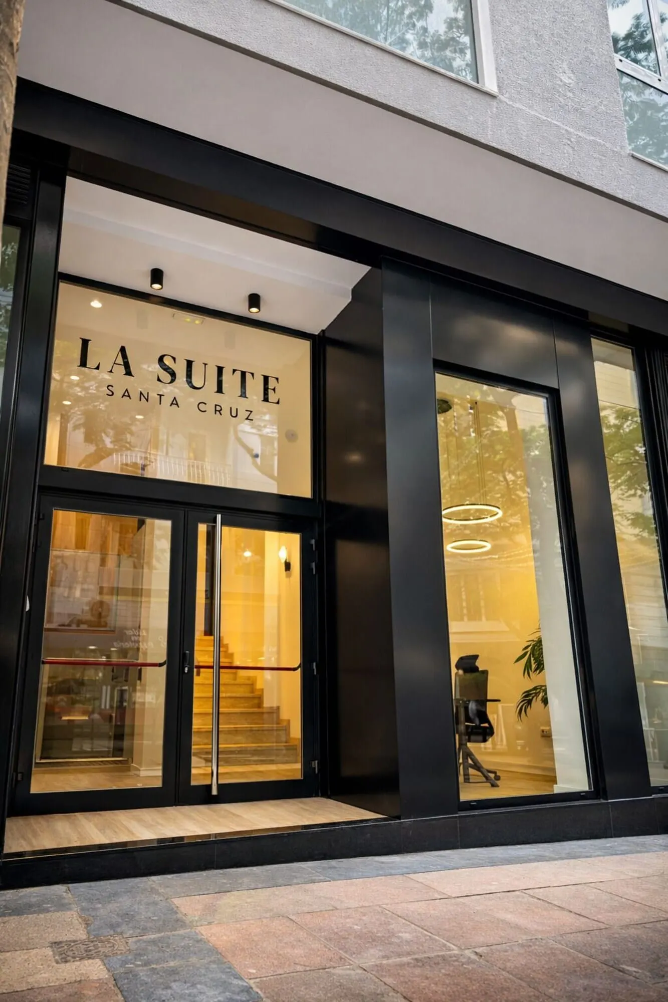 Adonis La Suite: The exterior of La Suite Santa Cruz hotel with large glass doors and a modern facade