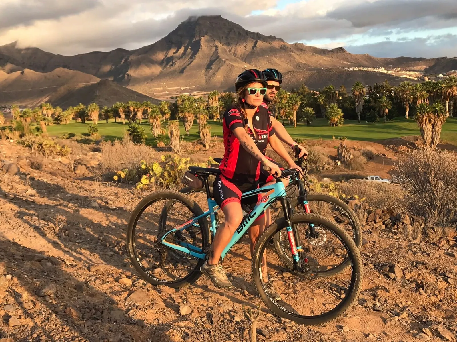 Ona Palm Beach: Two people on a mountain bike trail with a mountainous backdrop
